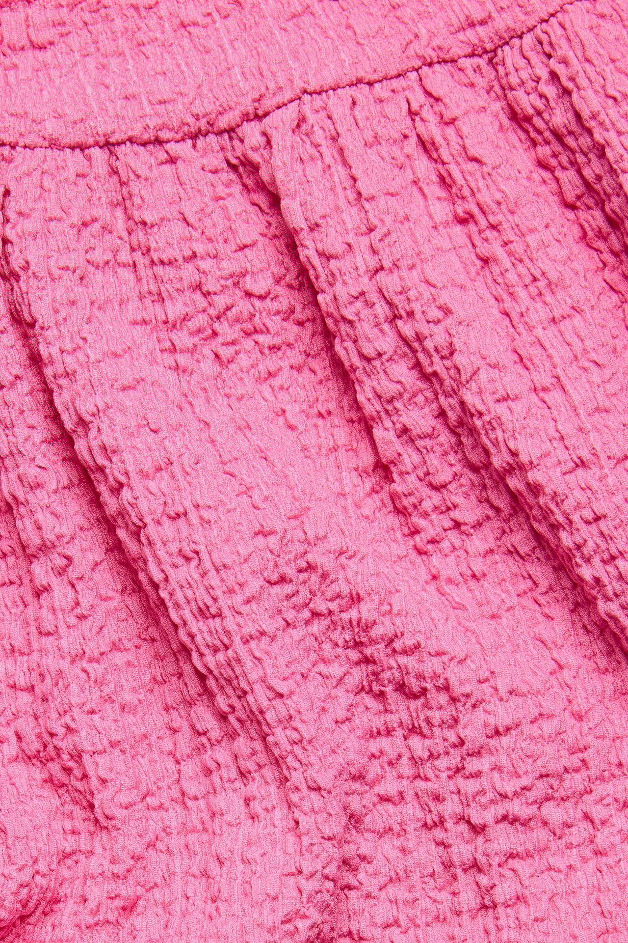 Zbliżenie na różowy, marszczony materiał sukienki z dżerseju.