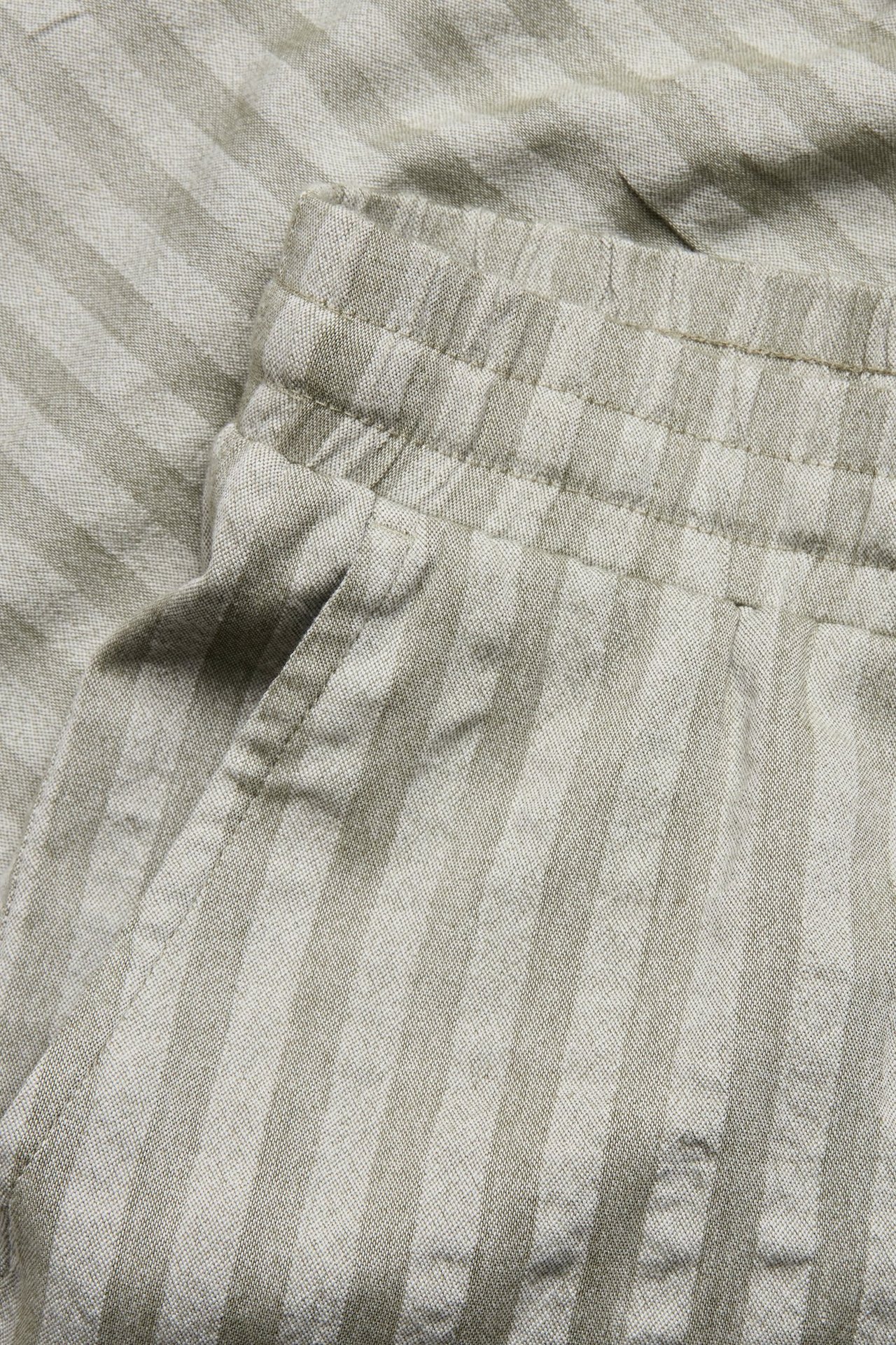 Zbliżenie na zielone, pasiasty szorty z seersuckeru z elastycznym pasem i boczną kieszenią.