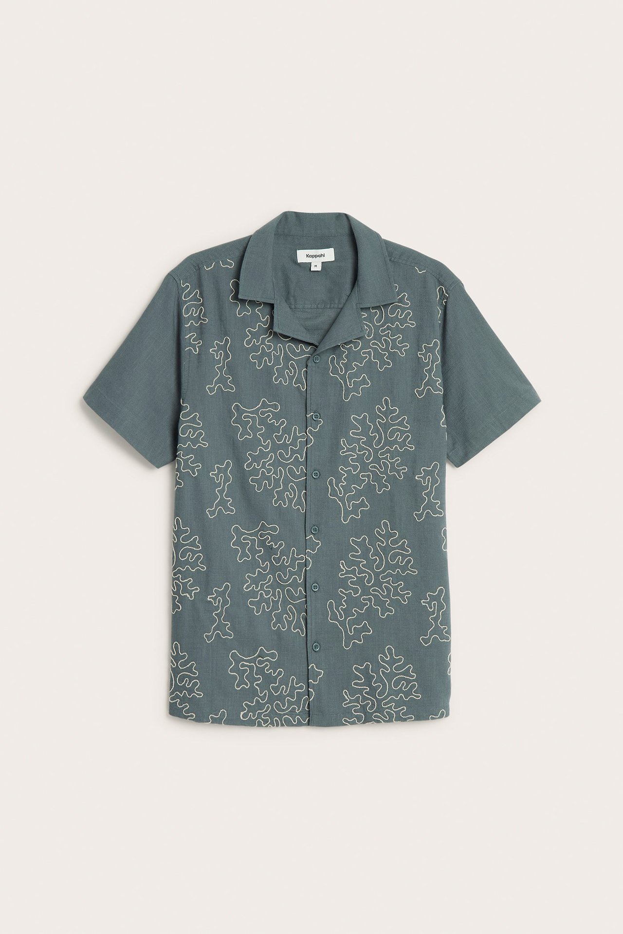 Edestä näkymä miesten tummanharmaasta puuvillaisesta lyhythihaisesta kauluspaidasta, jossa on vaalea abstrakti kirjonta.