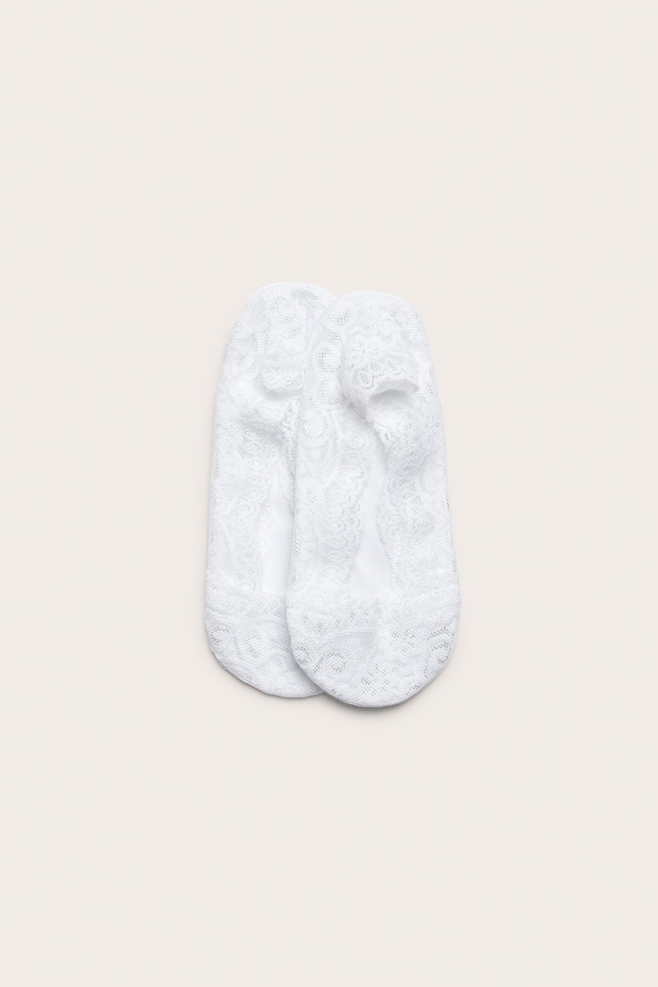 Widok z góry na parę białych koronkowych stopek z delikatnym wzorem.