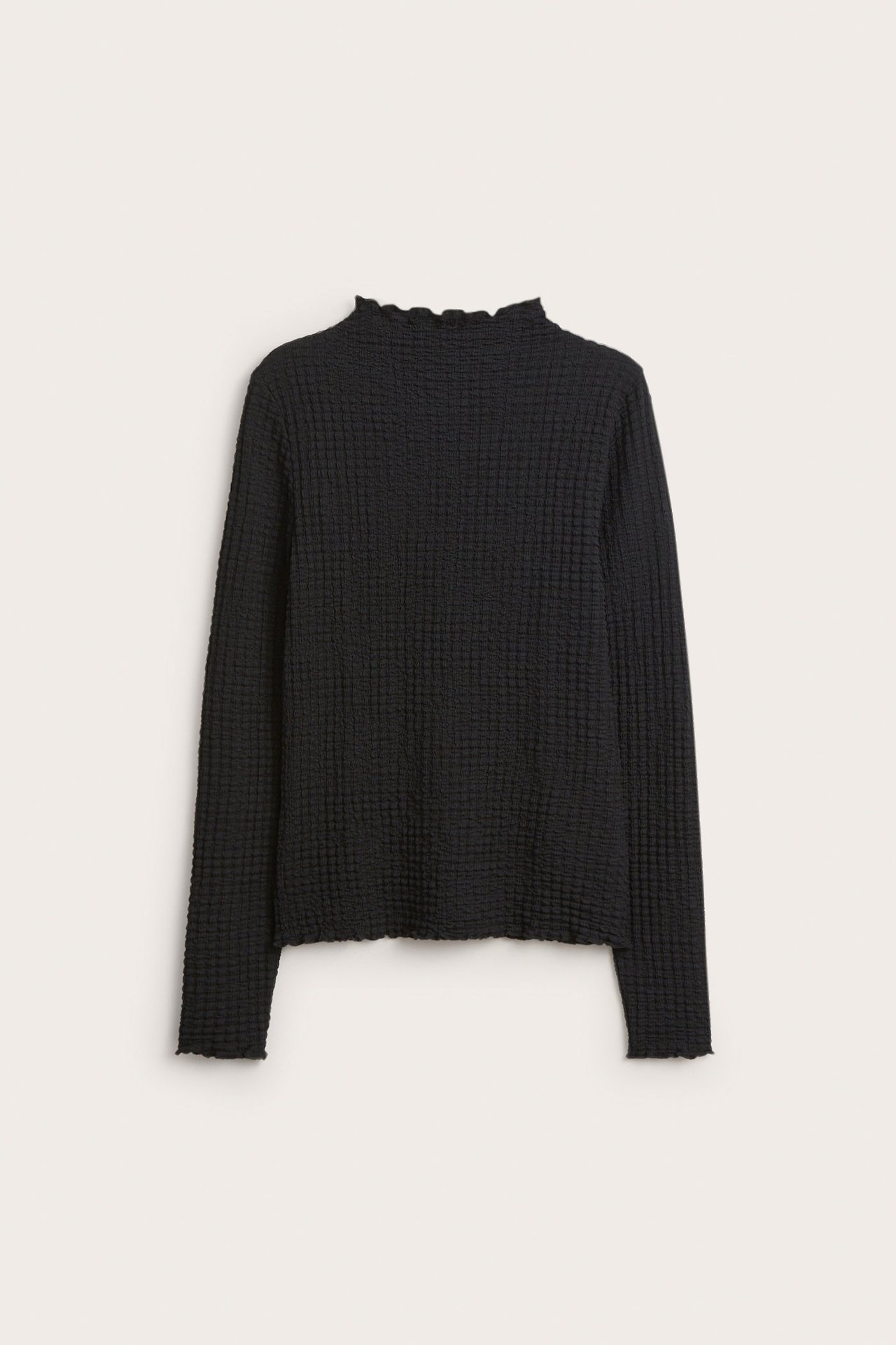 Widok z przodu czarnego, długiego, strukturalnego topu z falbankowym półgolfem i wykończeniem babylock.