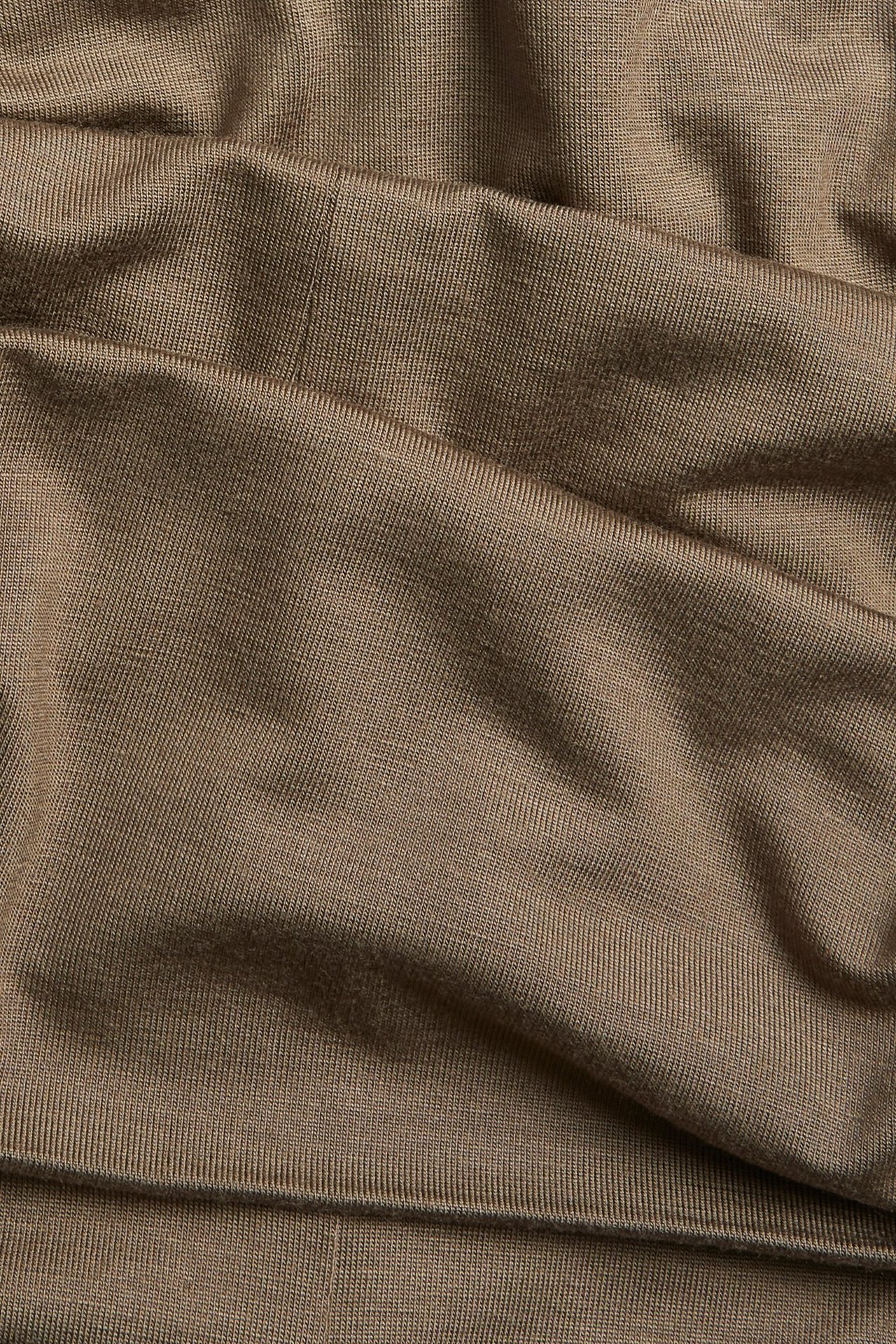 Zbliżenie miękkiego, udrapowanego brązowego materiału z dzianiny wiskozowej na szerokie spodnie.