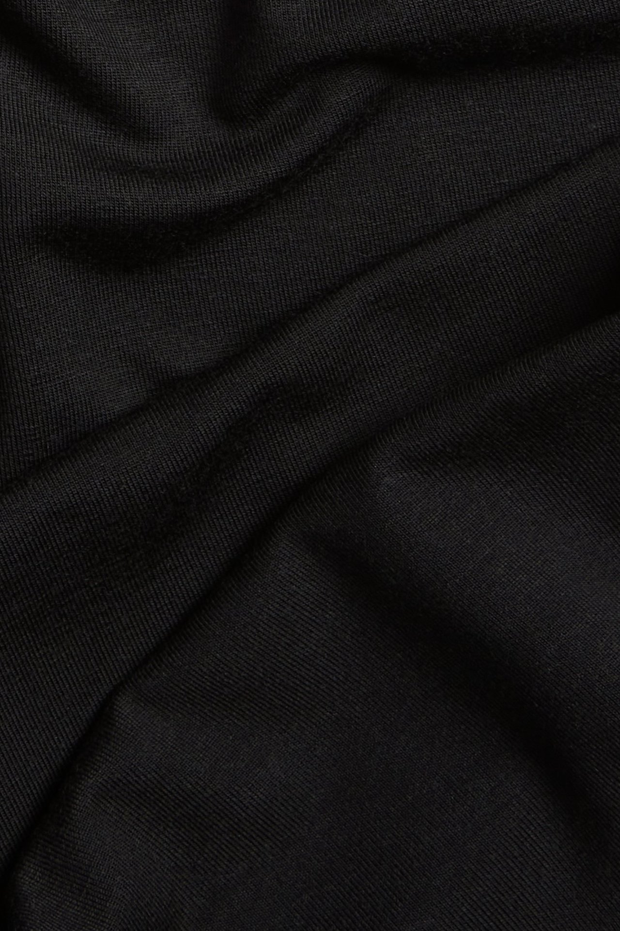 Zbliżenie czarnego, jednolitego materiału z wiskozy i elastanu z miękkimi fałdami, na szorty rowerowe.