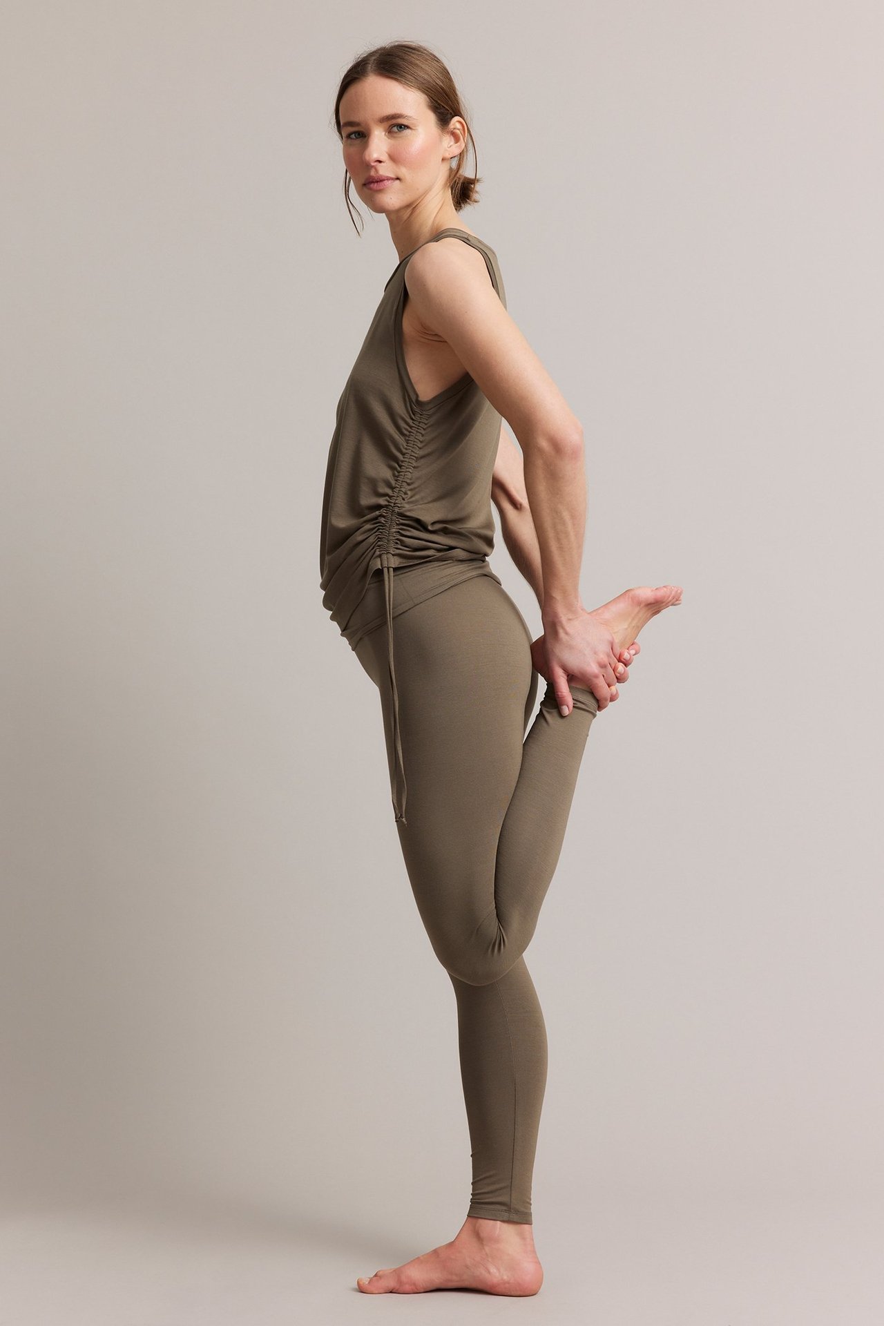 Sivukuva naisesta ruskeissa viskoosi loungewear-leggingseissä ja yhteensopivassa rypytetyssä hihattomassa topissa.