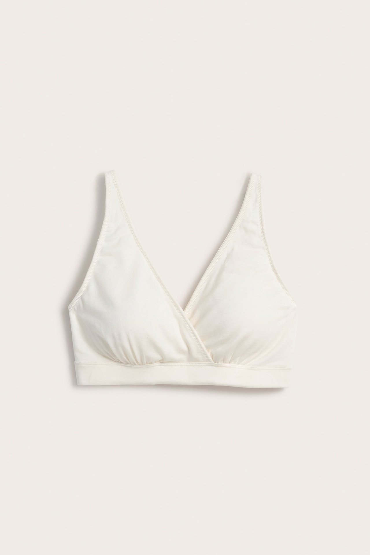 Frontvisning av en hvit omslags-BH-topp i myk Tencel-blanding, med brede stropper og elastisk bånd.