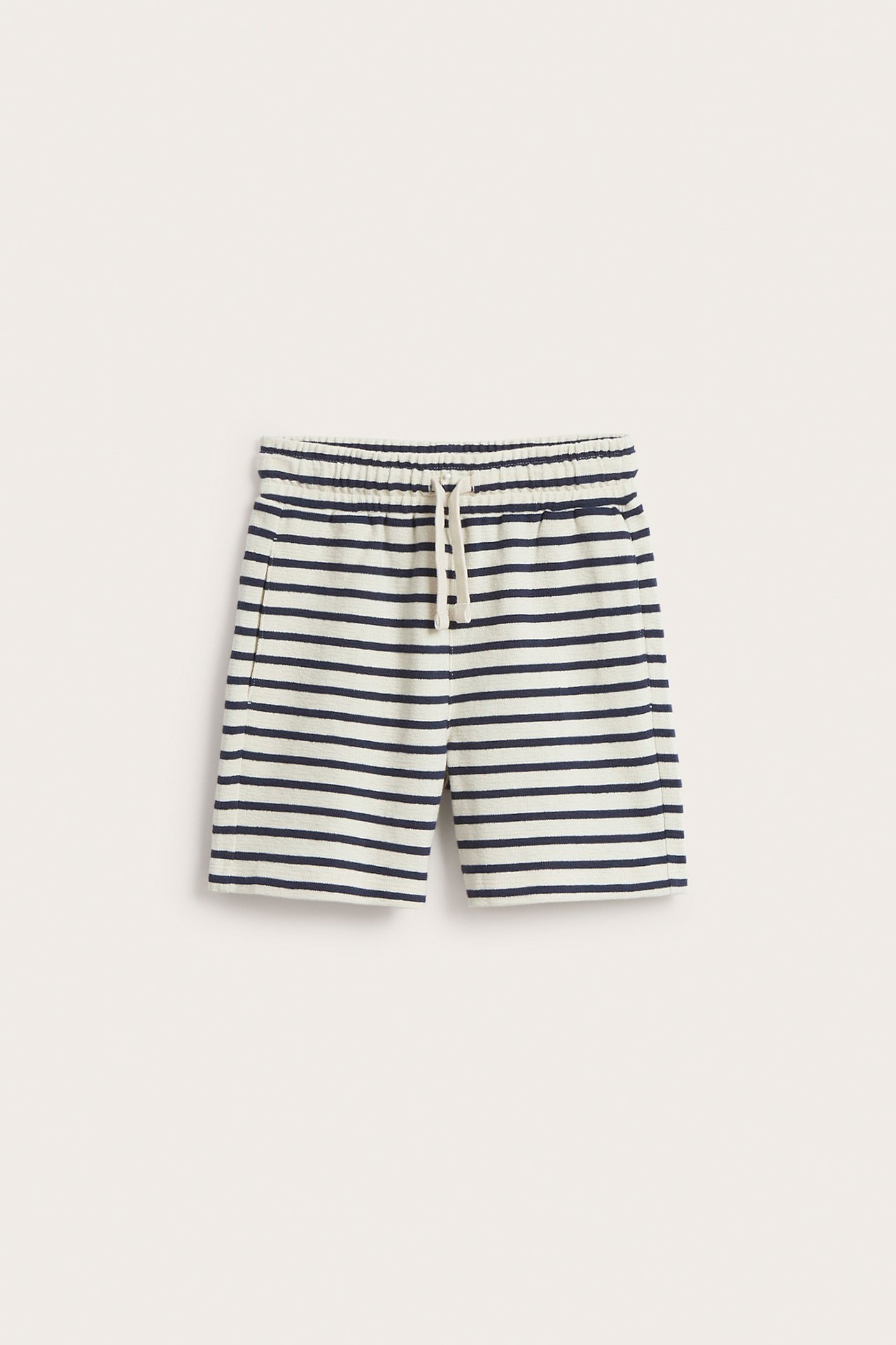 Forfra: Lysebeige og marineblå stripete bomullsshorts med elastisk snøring i midjen og sidelommer.