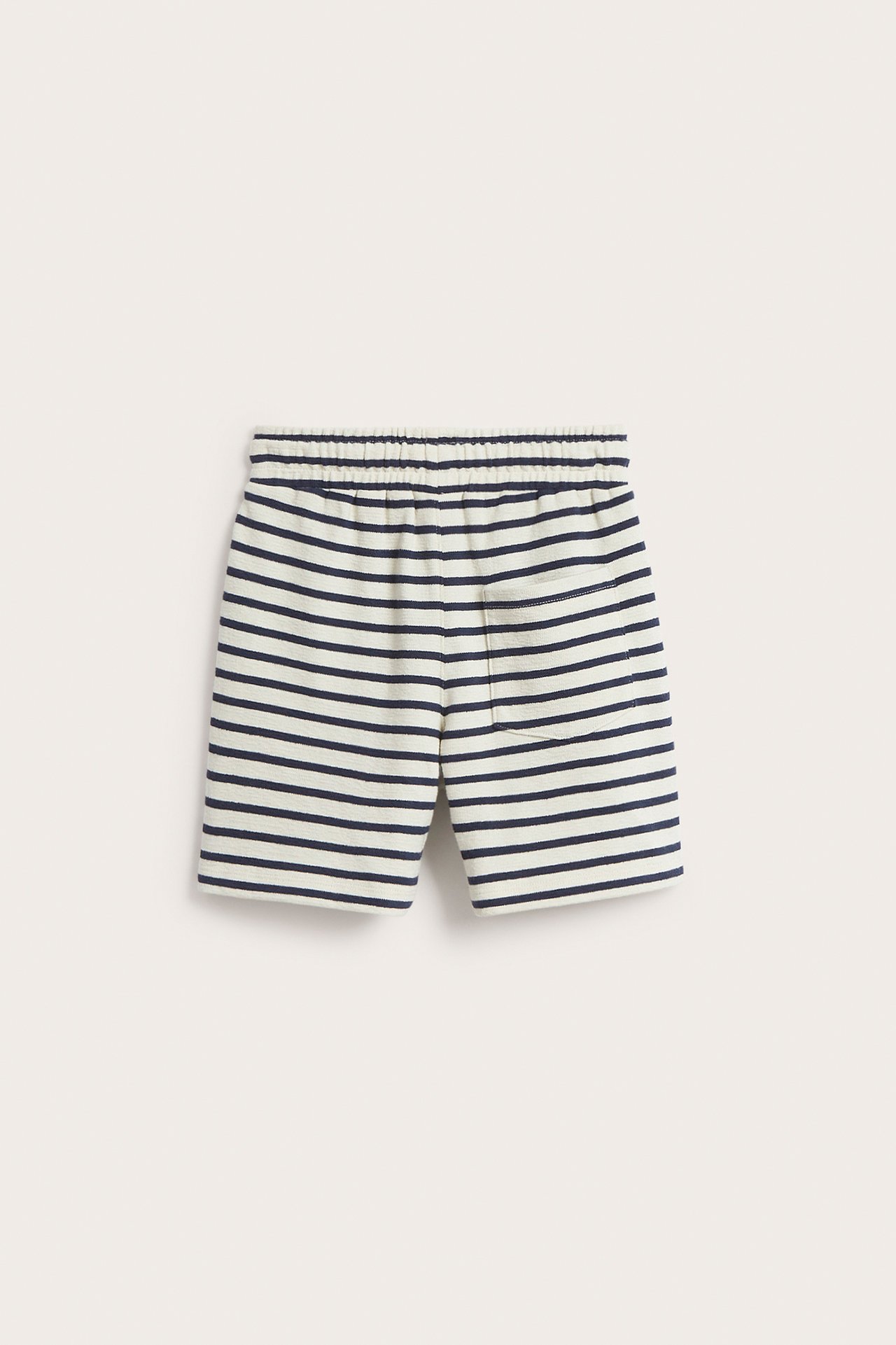 Forfra: Barneshorts i lys beige bomull med mørkeblå striper, elastisk midje og en lomme.