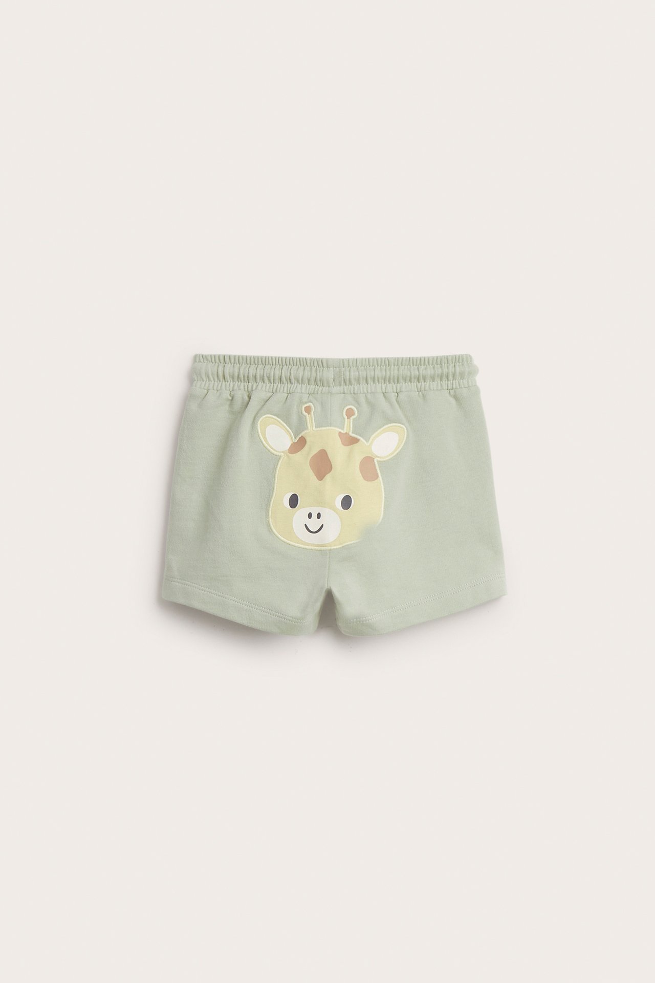 Bakfra: babyens lysegrønne bomullsshorts med elastisk midje og en sjiraffapplikasjon.