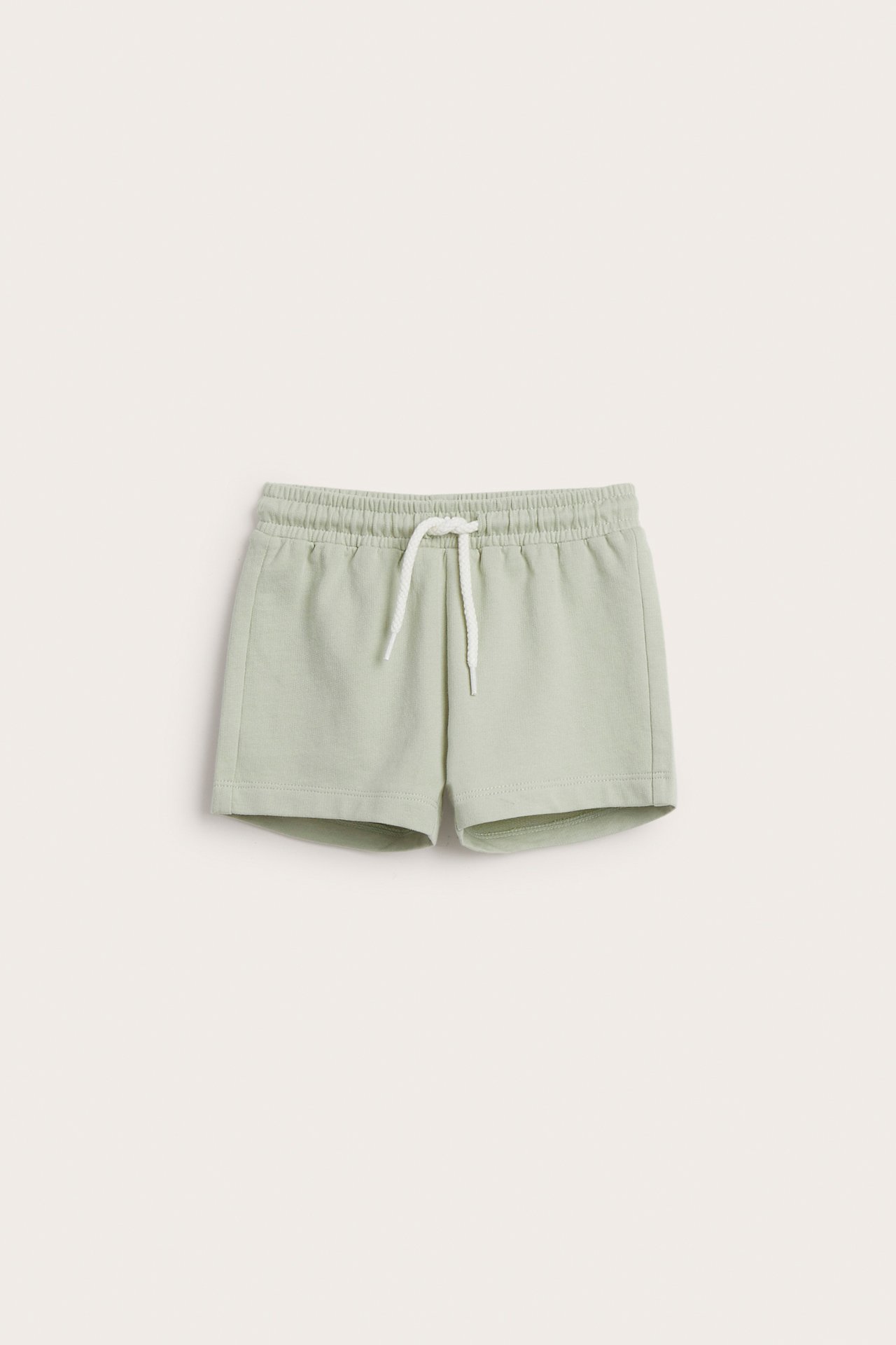 Frontvisning av lysegrønne bomulls-babyshorts med elastisk snøring i midjen.