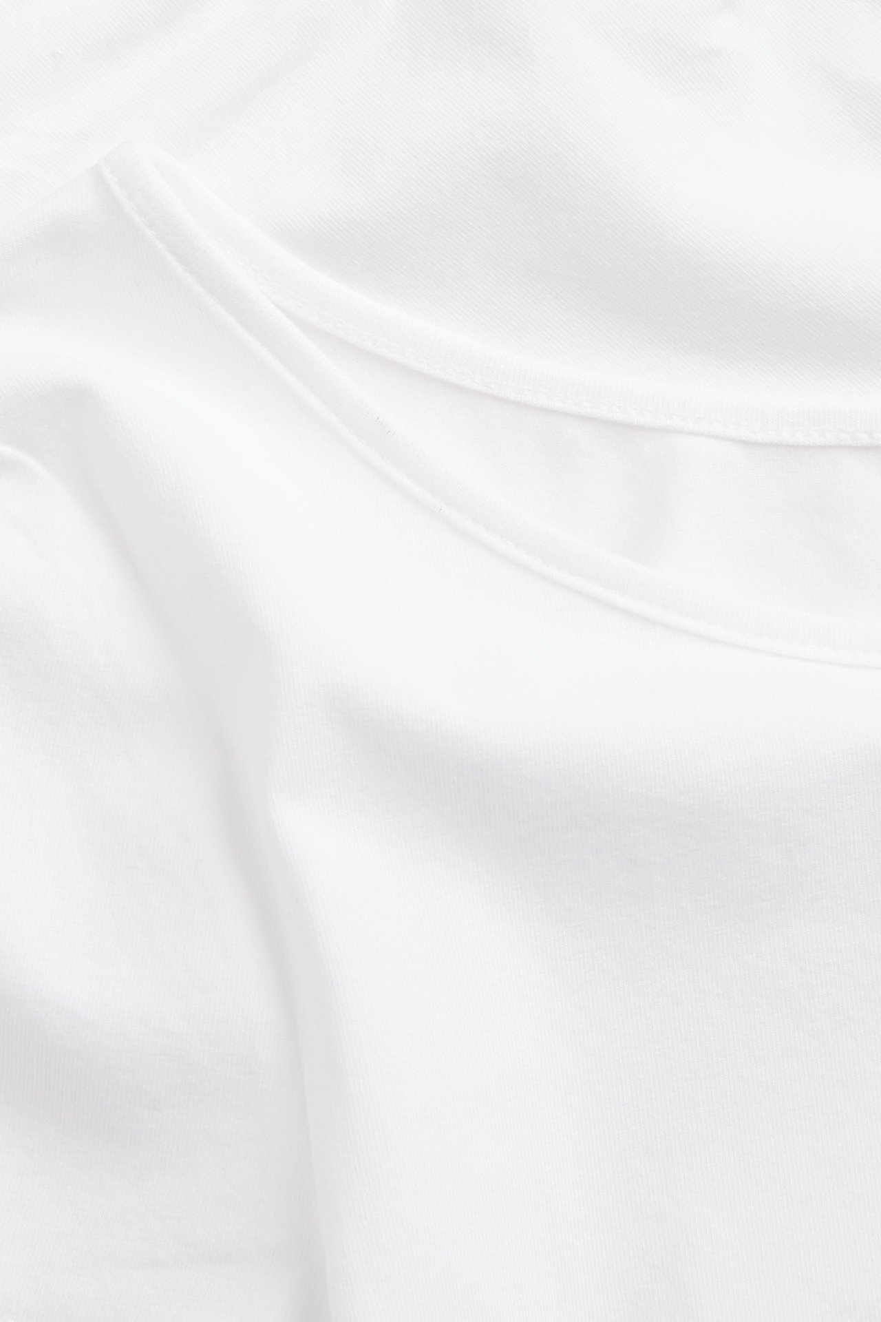 Zbliżenie na gładki, biały, dopasowany top z głębokim dekoltem.