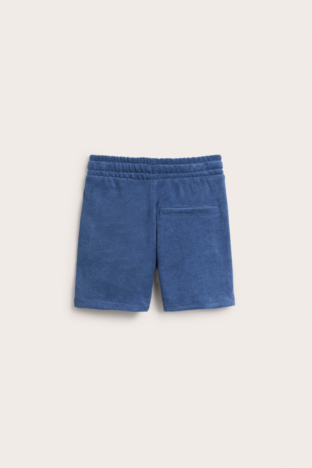 Bakfra mørkeblå frottéshorts med elastisk linning og en baklomme.