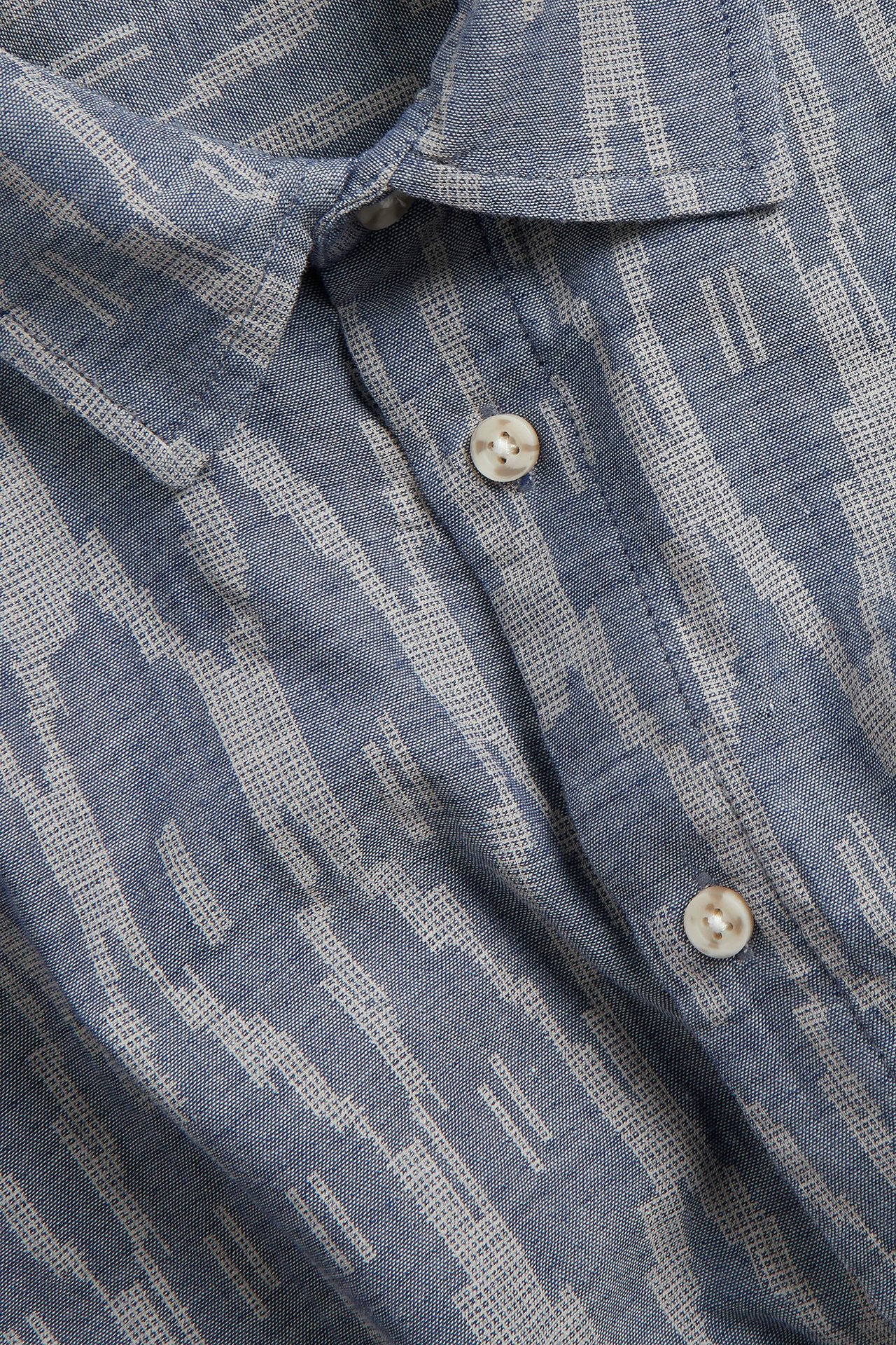 Zbliżenie męskiej granatowej koszuli z krótkim rękawem, bawełnianej, we wzory, z białymi guzikami i normalnym kołnierzem.