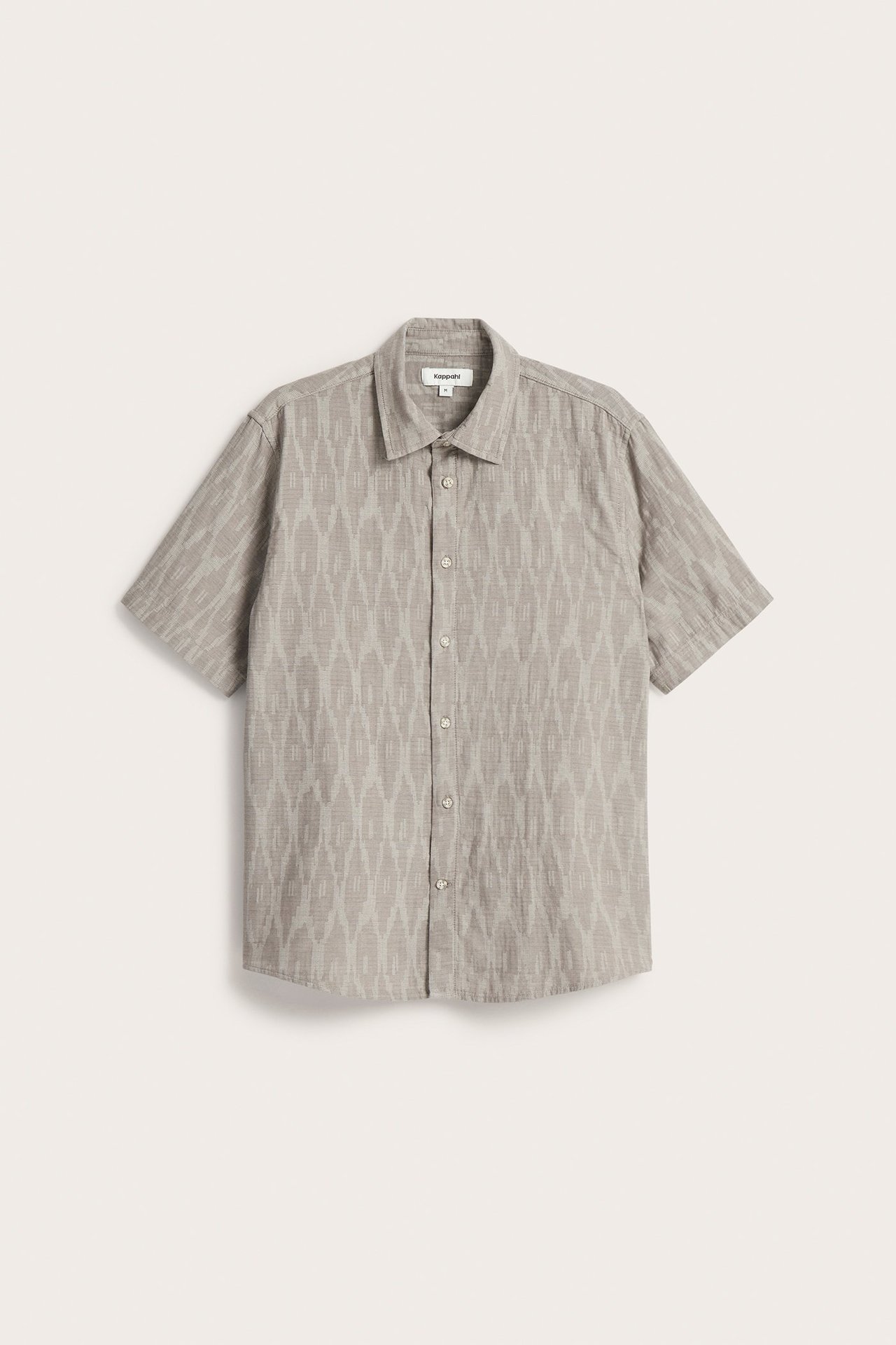 Edestä kuvattu miesten vaaleanruskea kuviollinen lyhythihainen puuvillapaita, jossa on kaulus ja napitus.