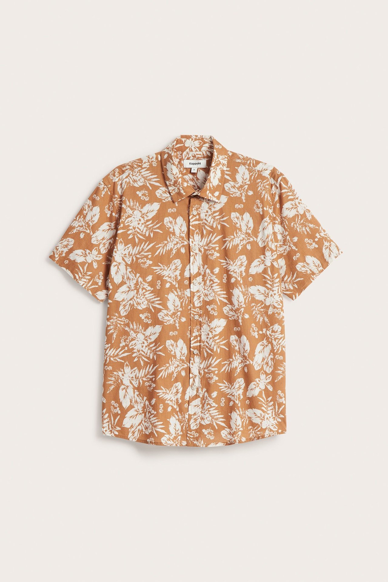 Framifrån: brun kortärmad herrskjorta i bomull med vitt blommigt mönster och knappar fram.