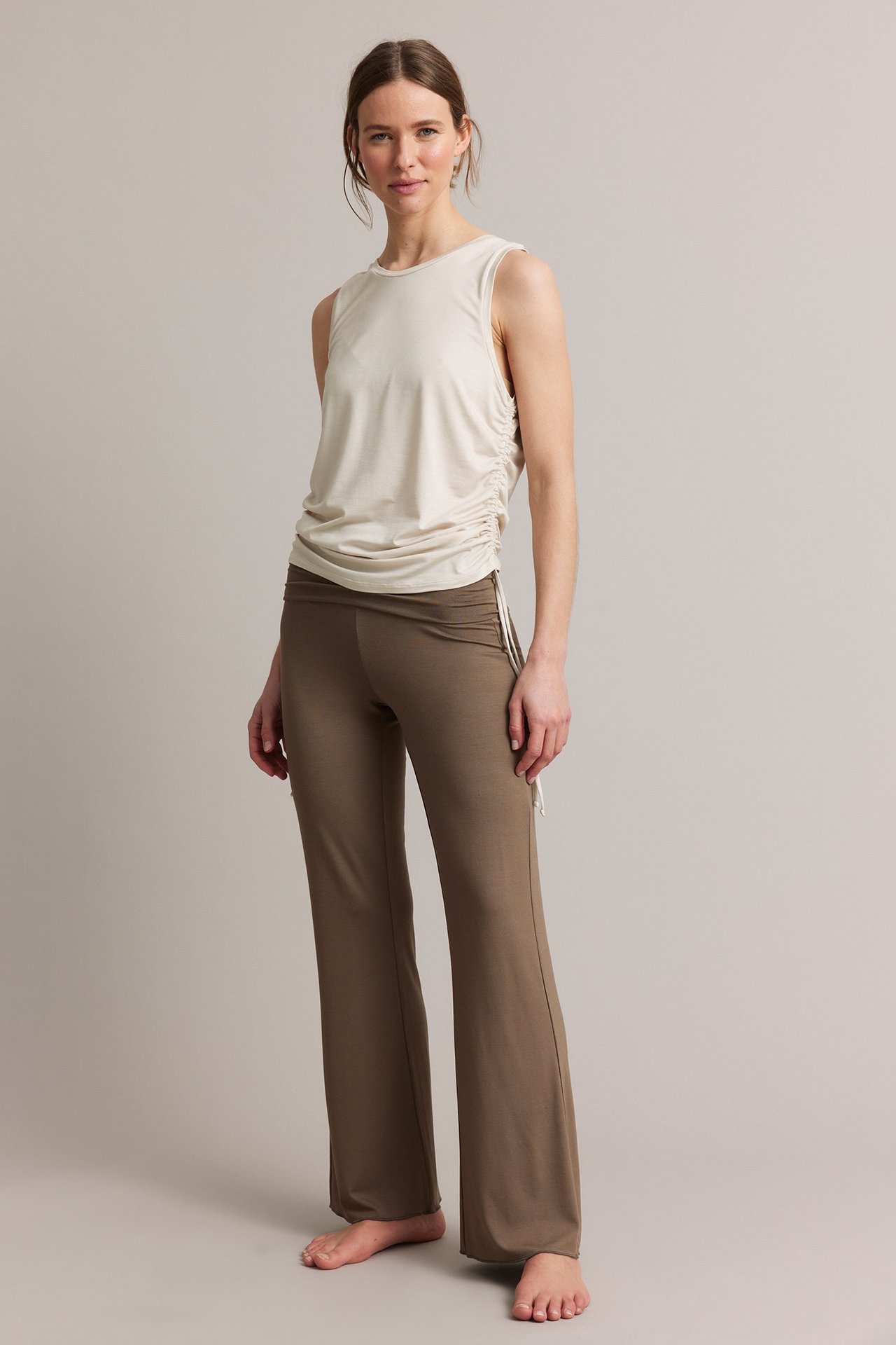Frontbilde: kvinne i lys beige tencel-topp med snøring i siden og brune vide bukser.