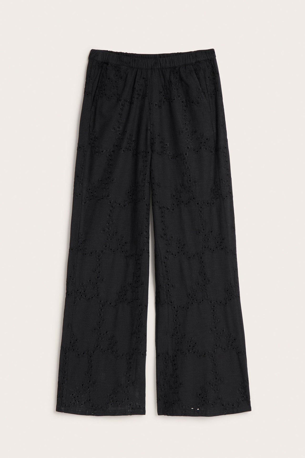 Framifrån: svarta vida bomullsbyxor med broderie anglaise, resår i midjan och sidfickor.