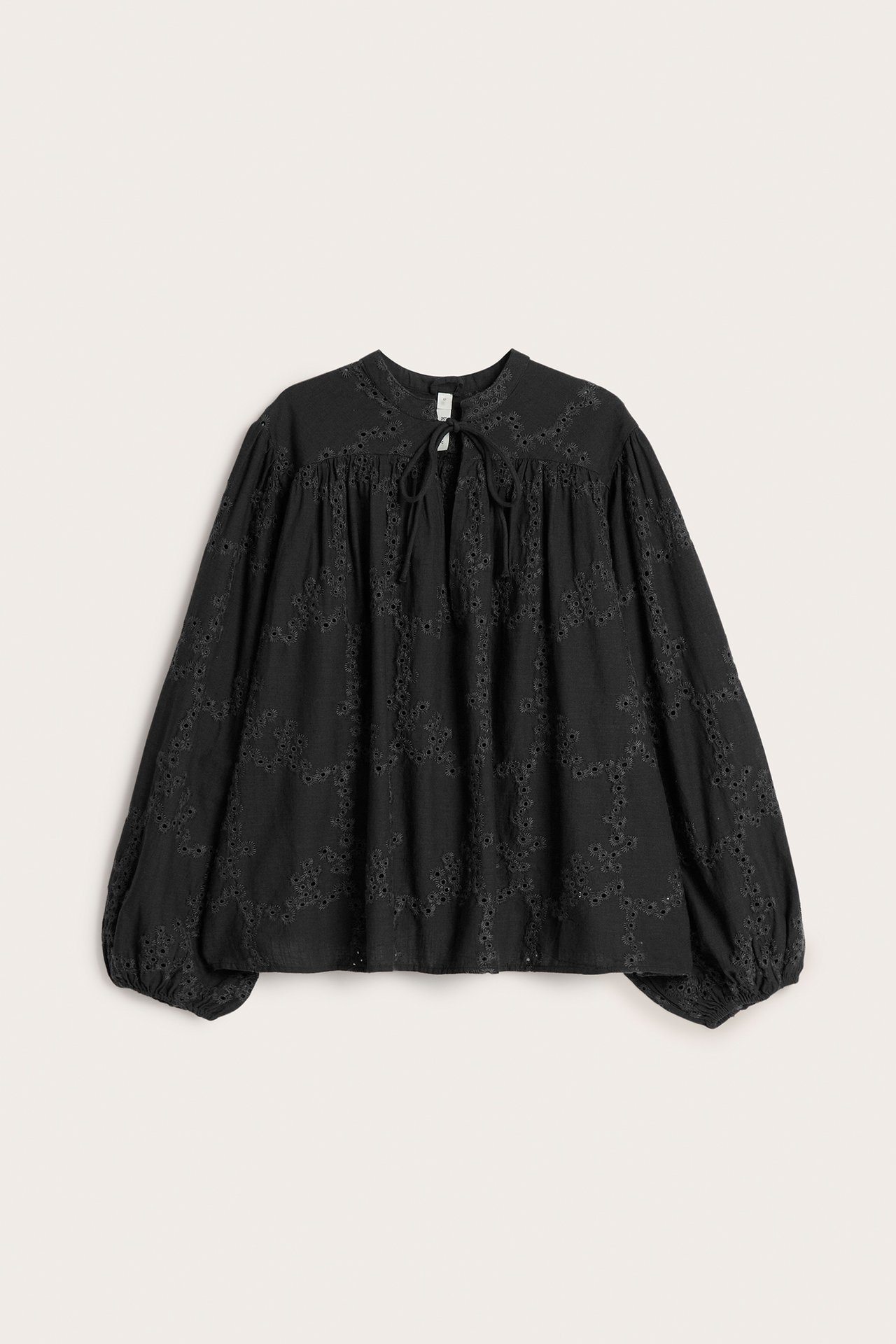 Frontvisning: svart bomullsbluse med broderie anglaise, ståkrage, knytebånd og elastiske mansjetter.