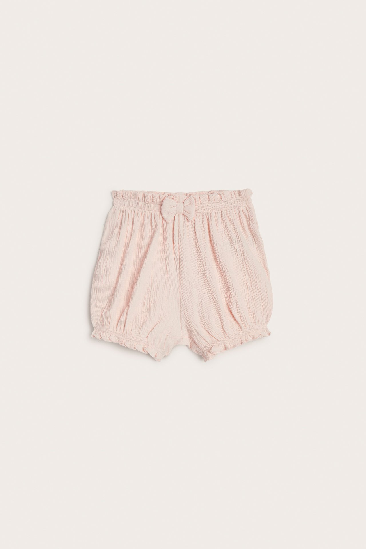 Forfra: Babyens lys rosa krøllete jerseyshorted med puffete passform, elastisk midje og sløyfe.