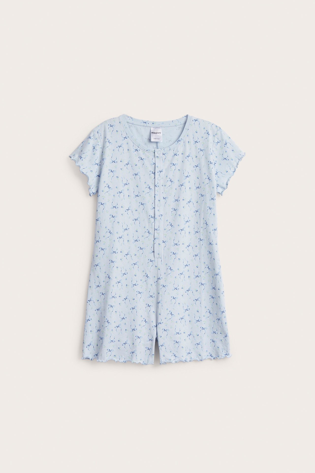 Framifrån: Ljusblå pyjamas-jumpsuit i bomull för barn med korta ärmar, knappar framtill och rosettmönster.