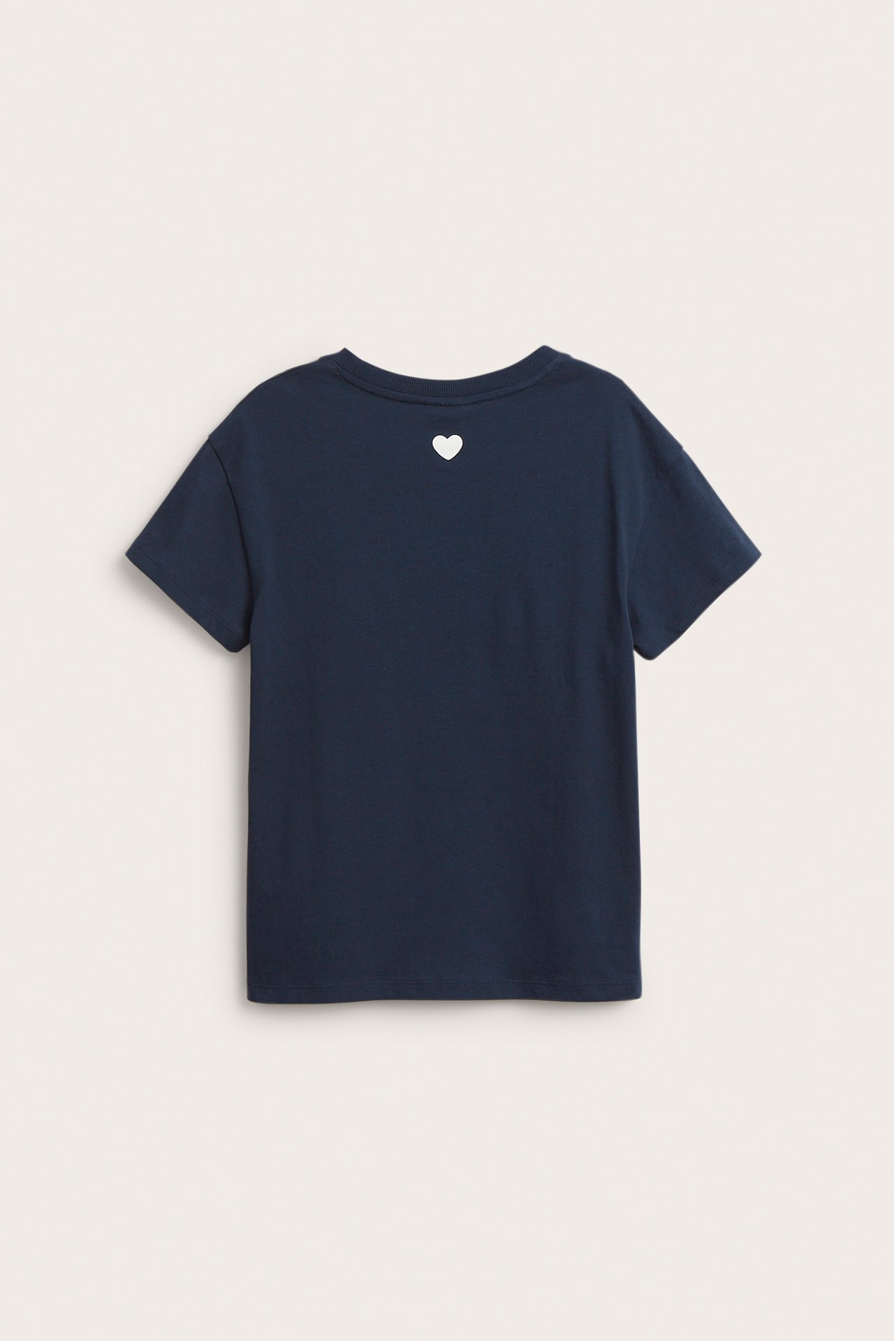Widok z tyłu: granatowy bawełniany T-shirt dziecięcy z małym białym sercem nadrukowanym na karku.