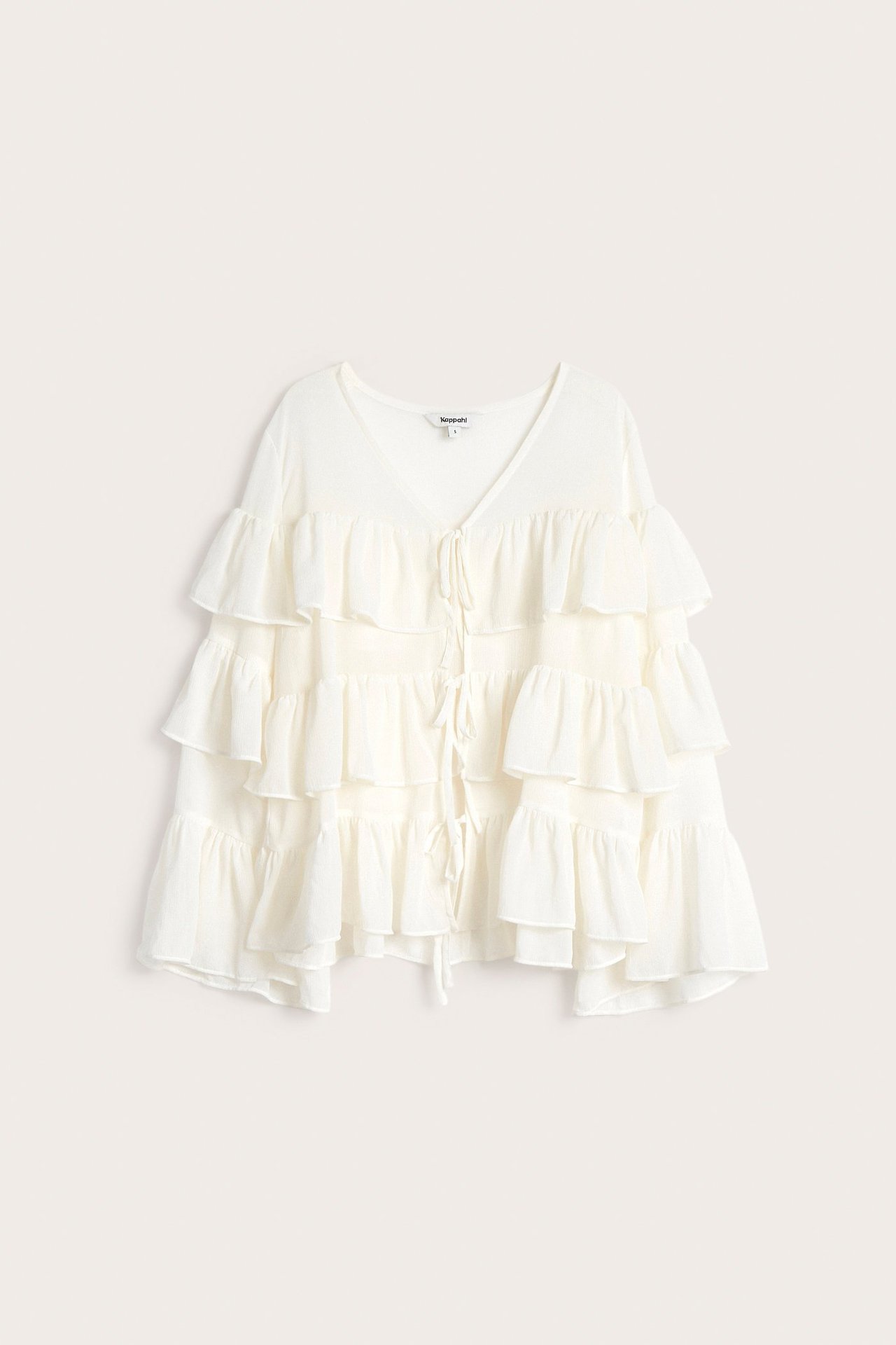 Framifrån, offwhite chiffongblus med volanger, V-ringning och knytband framtill.