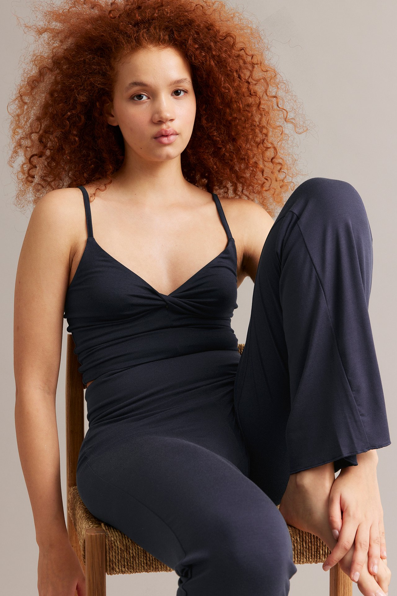 Frontutsikt av kvinne i en mørkeblå, vridd topp og matchende mørkeblå kosebukser.