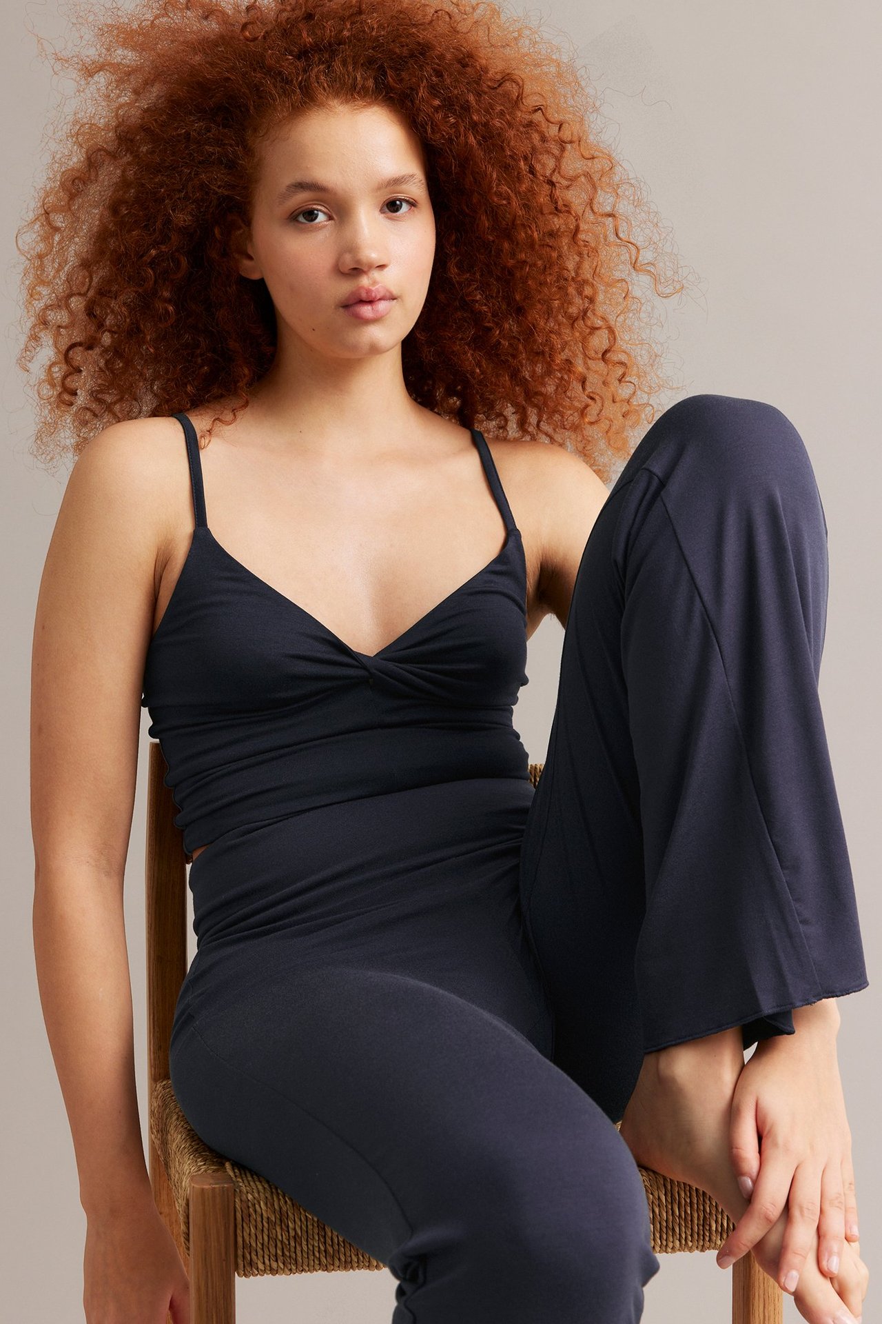 Widok z przodu kobiety w granatowym topie z wiązaniem i pasujących granatowych spodniach domowych.