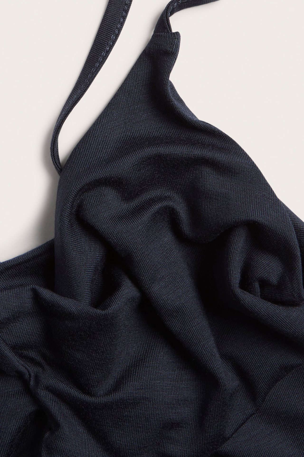 Zbliżenie na granatowy, jednolity top z miękkiej wiskozowej dzianiny z cienkim ramiączkiem.