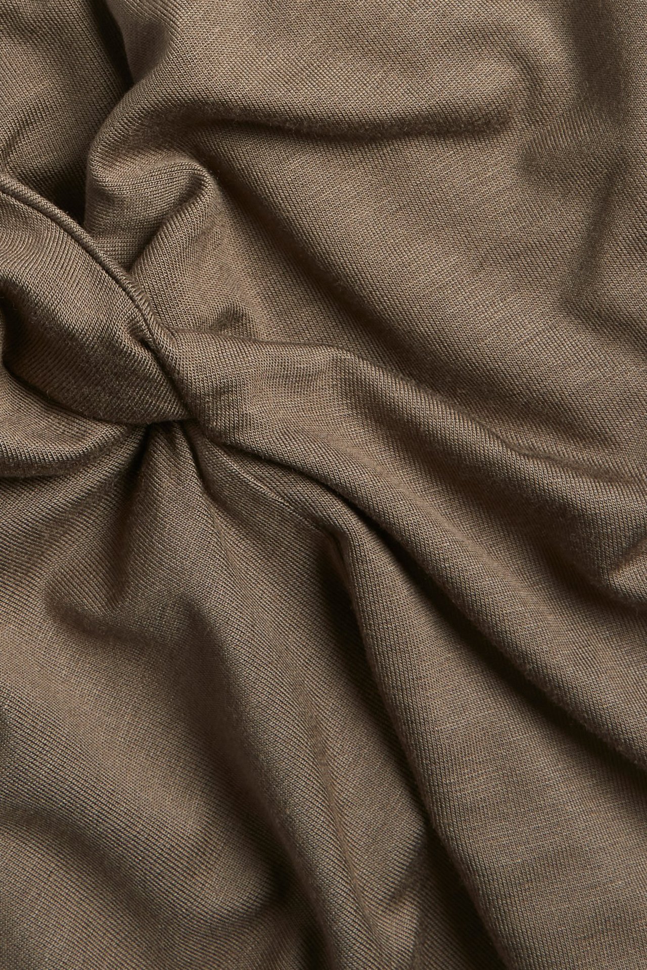 Zbliżenie brązowego topu z dzianiny wiskozowej z ozdobnym skręconym dekoltem.