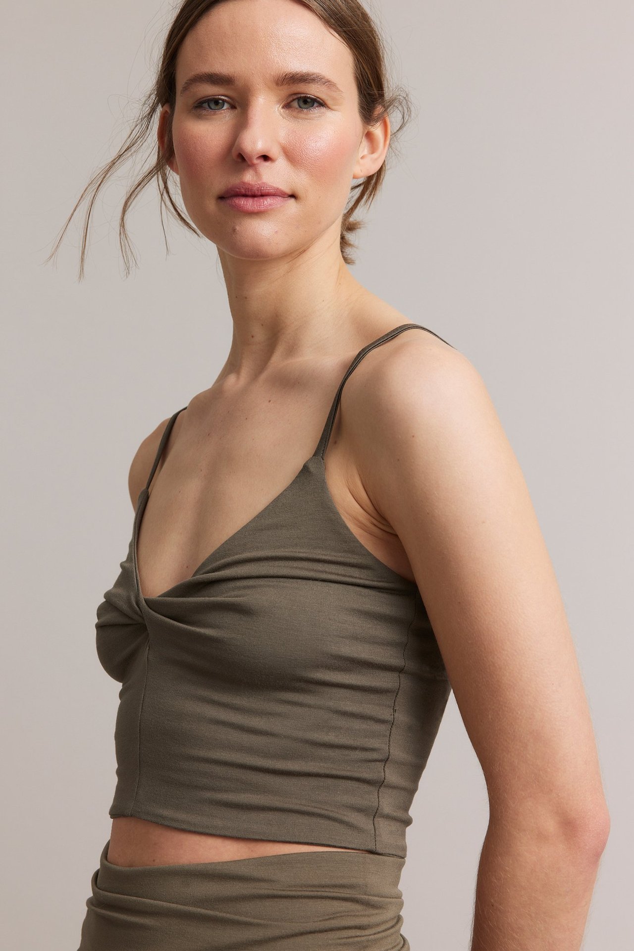 Frontbilde: Kvinne i brun viskoseblanding kort loungetopp med vridd V-hals og tynne stropper.