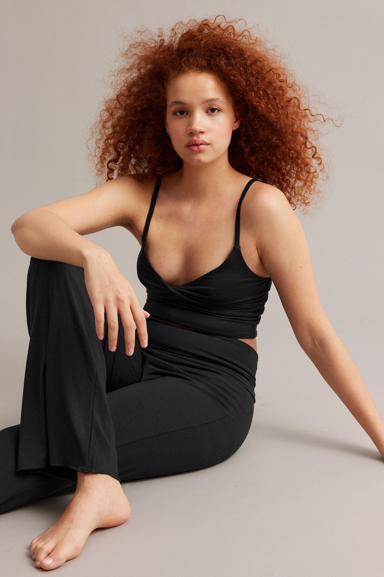 Framifrån, kvinna i svart omlott-linne och svarta vida byxor.