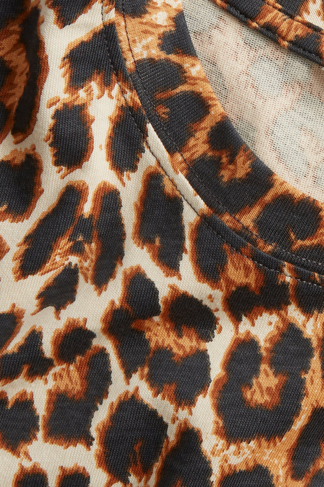 Nærbilde av en beige oversized bomulls-T-skjorte med brunt og svart leopardmønster.