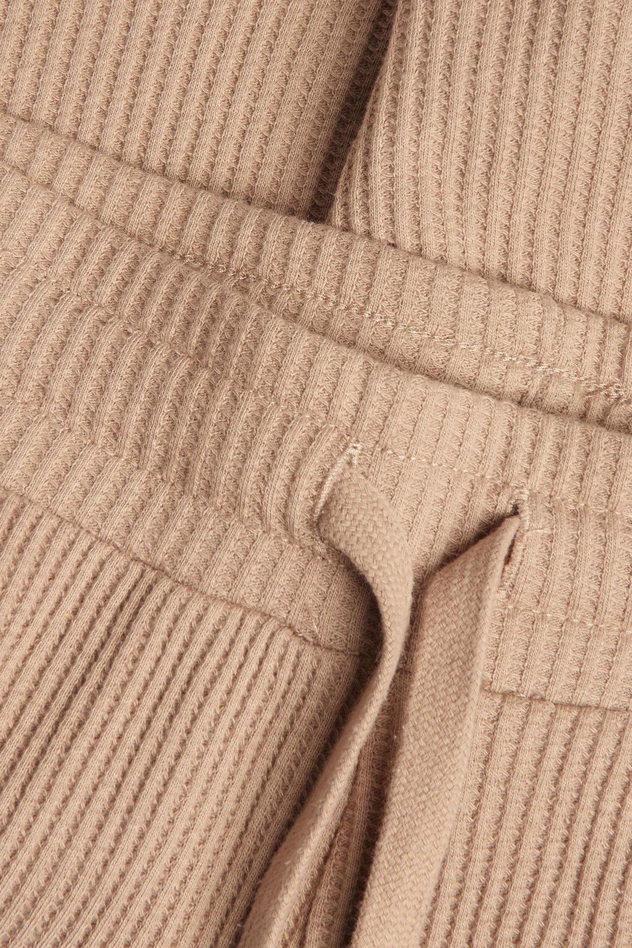 Zbliżenie na brązowe szorty z bawełny waflowej z elastycznym pasem i sznurkiem.