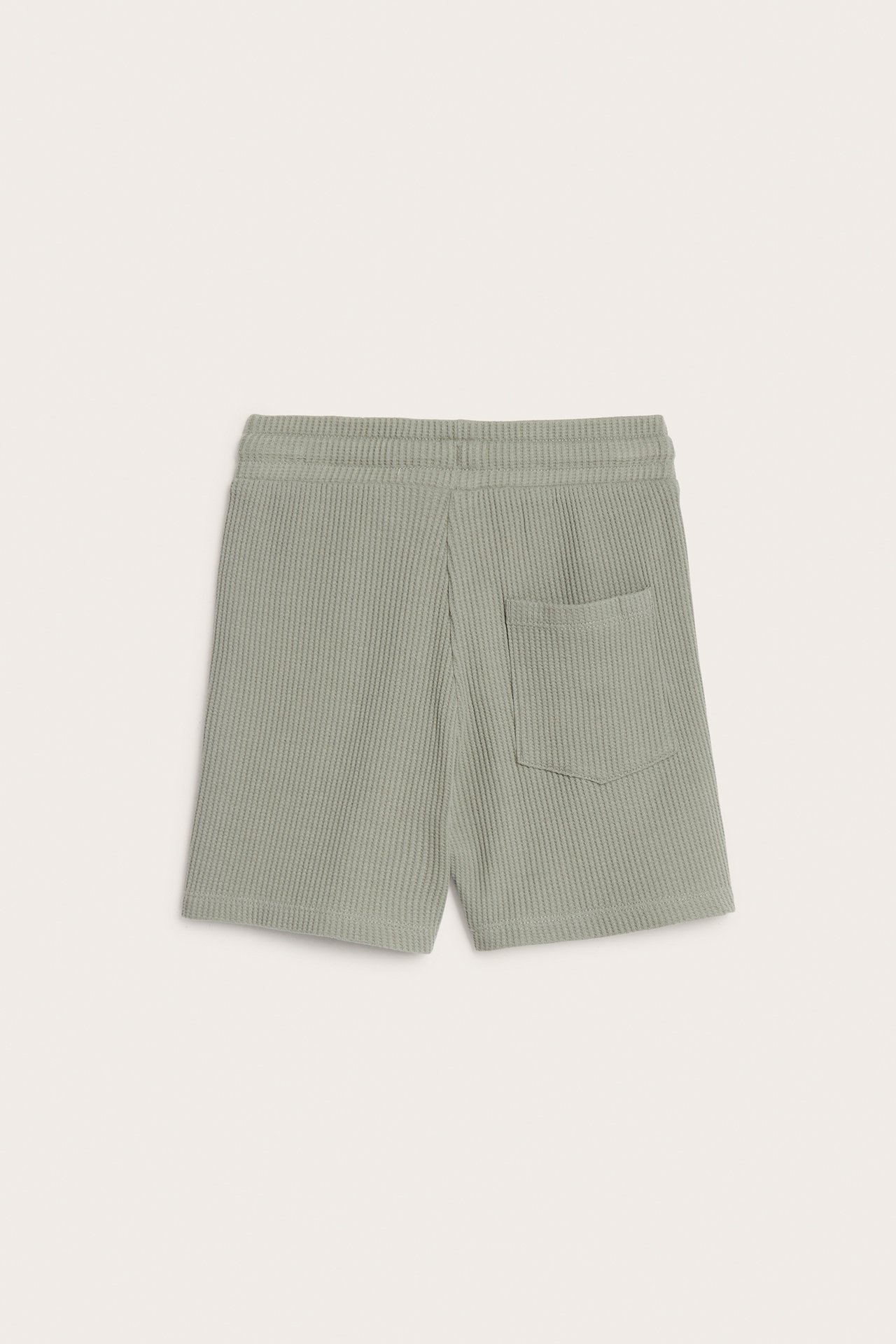 Bakfra, ensfargede grønne vaffelstrikkede bomullsshorts med elastisk midje og baklomme.