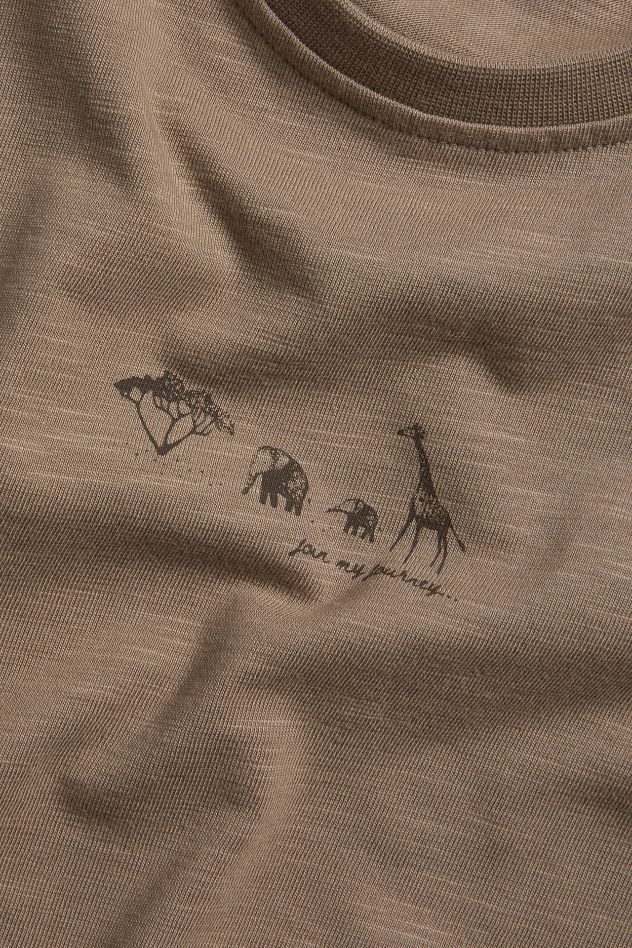 Zbliżenie brązowego t-shirtu z dżerseju slub z ciemnym nadrukiem zwierząt i tekstu.
