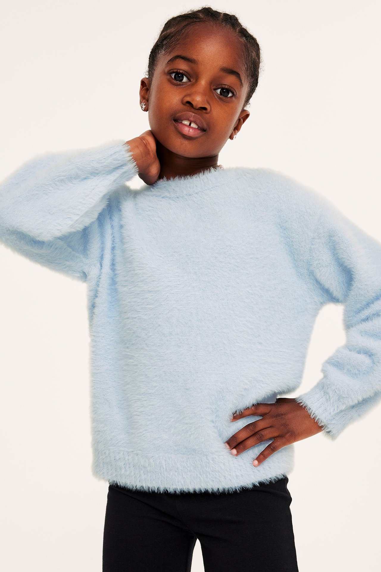Forfra: Et barn i en lyseblå fluffy strikket genser og svarte bukser.