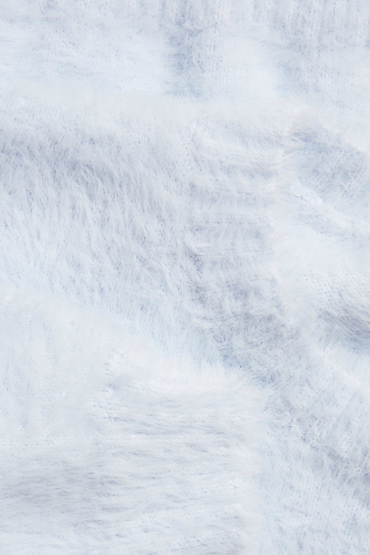 Zbliżenie jasnoniebieskiego jednolitego swetra z miękkiej przędzy piórkowej.