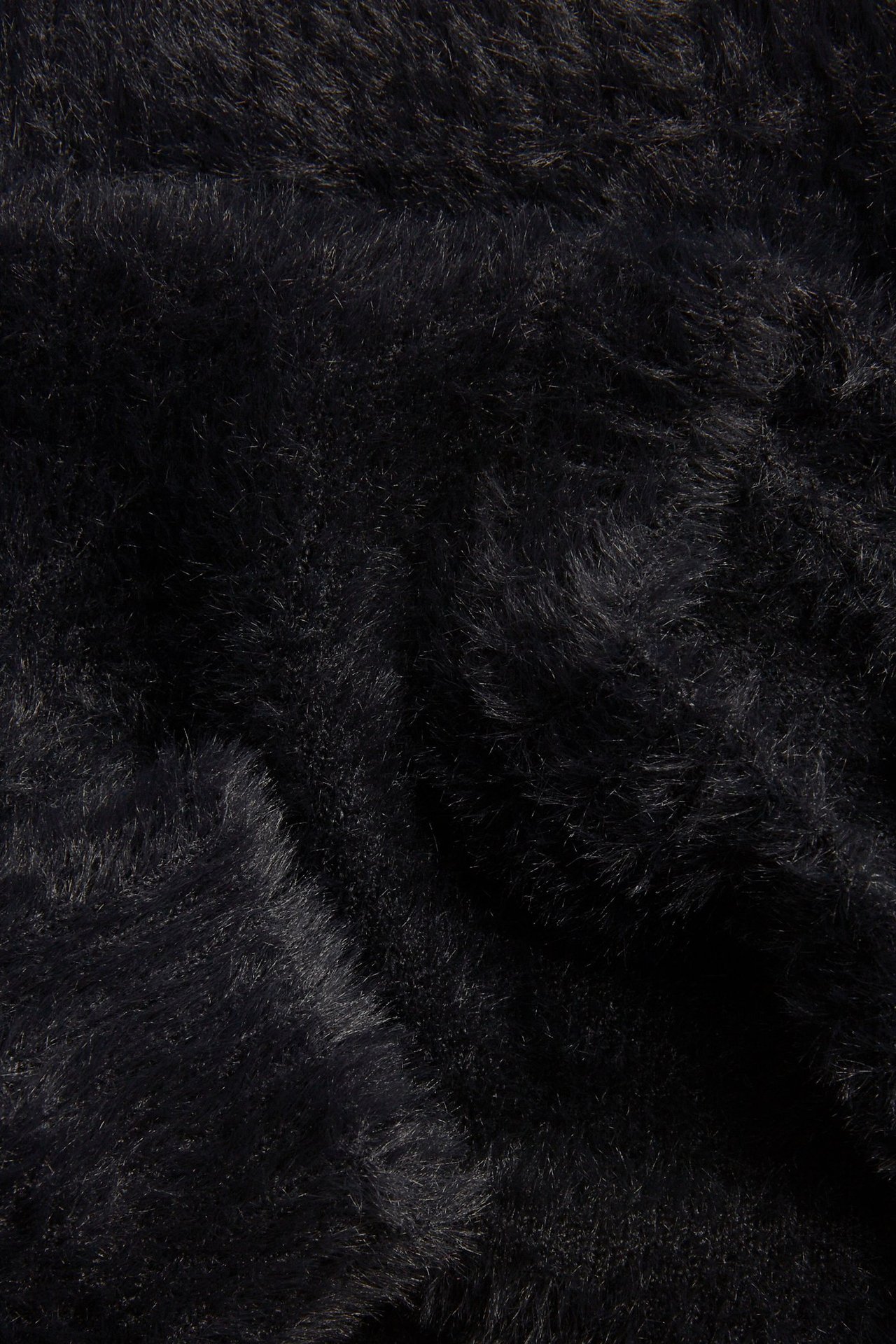 Zbliżenie na czarny materiał swetra z przędzy feather yarn, ukazujące jego miękką, puszystą teksturę.