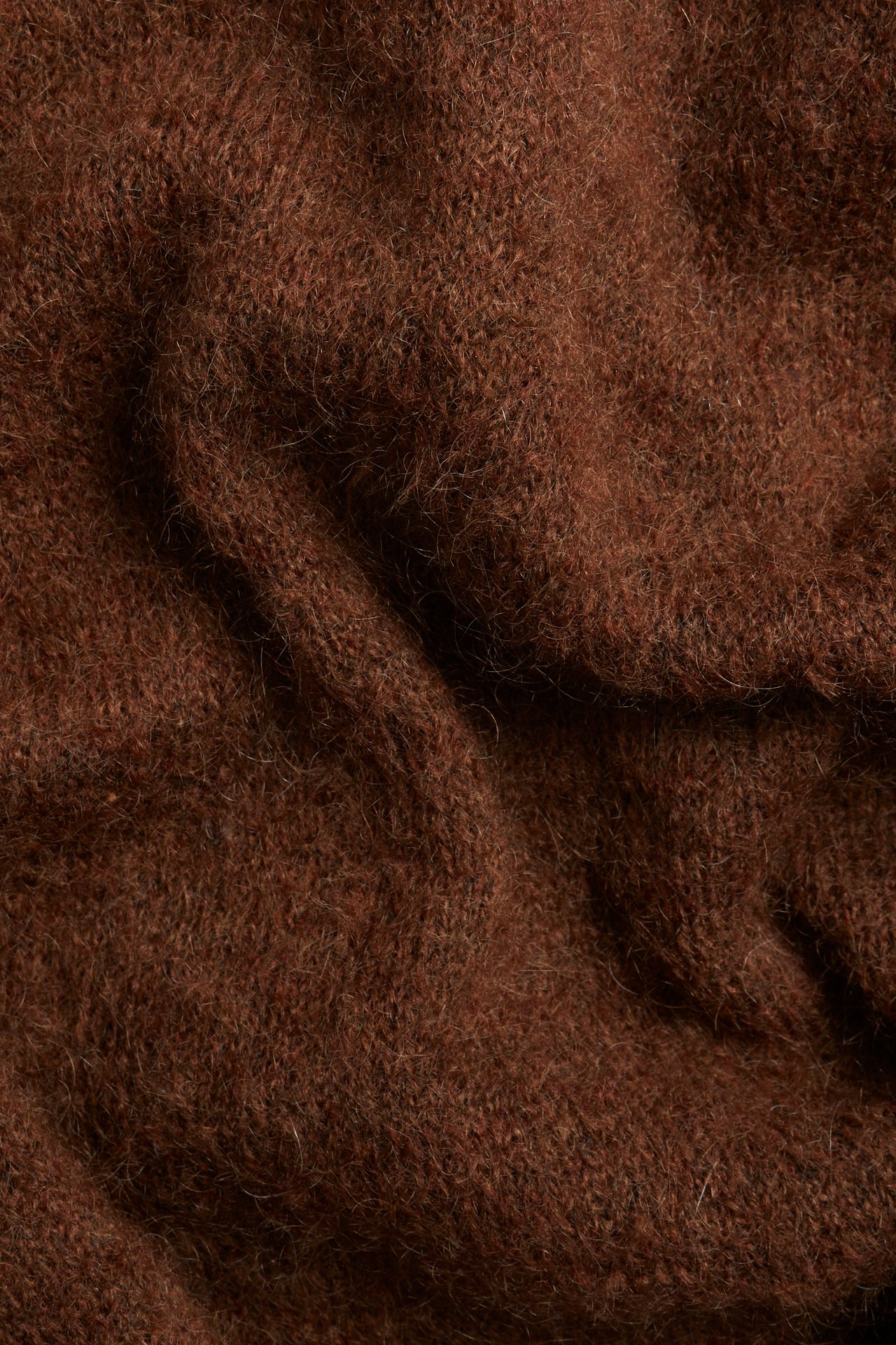 Lähikuva ruskeasta, yksivärisestä, pörröisestä neulepuserosta mohair- ja villasekoitteesta.