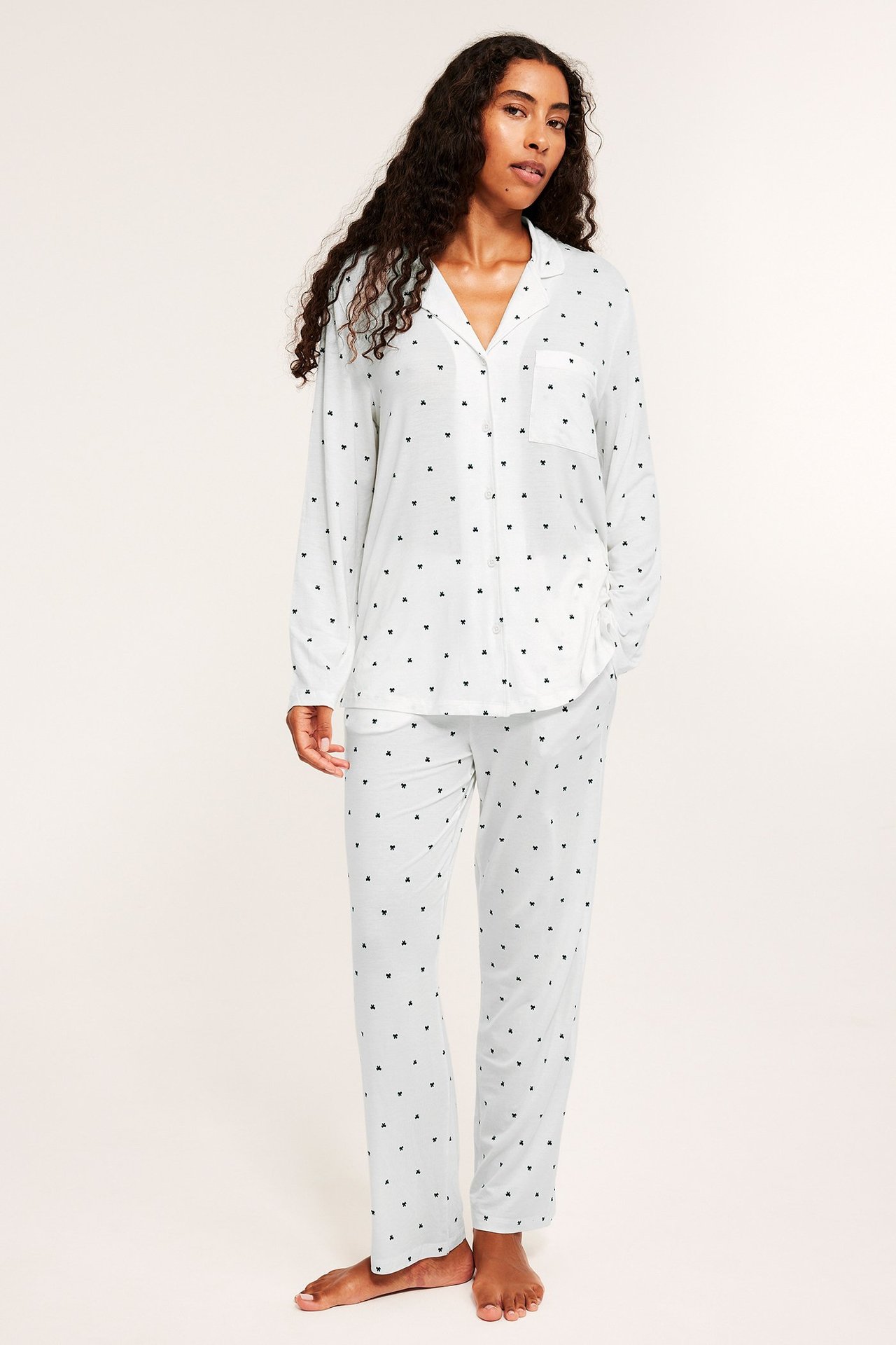 Edestäpäin, nainen yllään luonnonvalkoinen lyocell-pyjama pienellä mustalla sydänkuviolla.