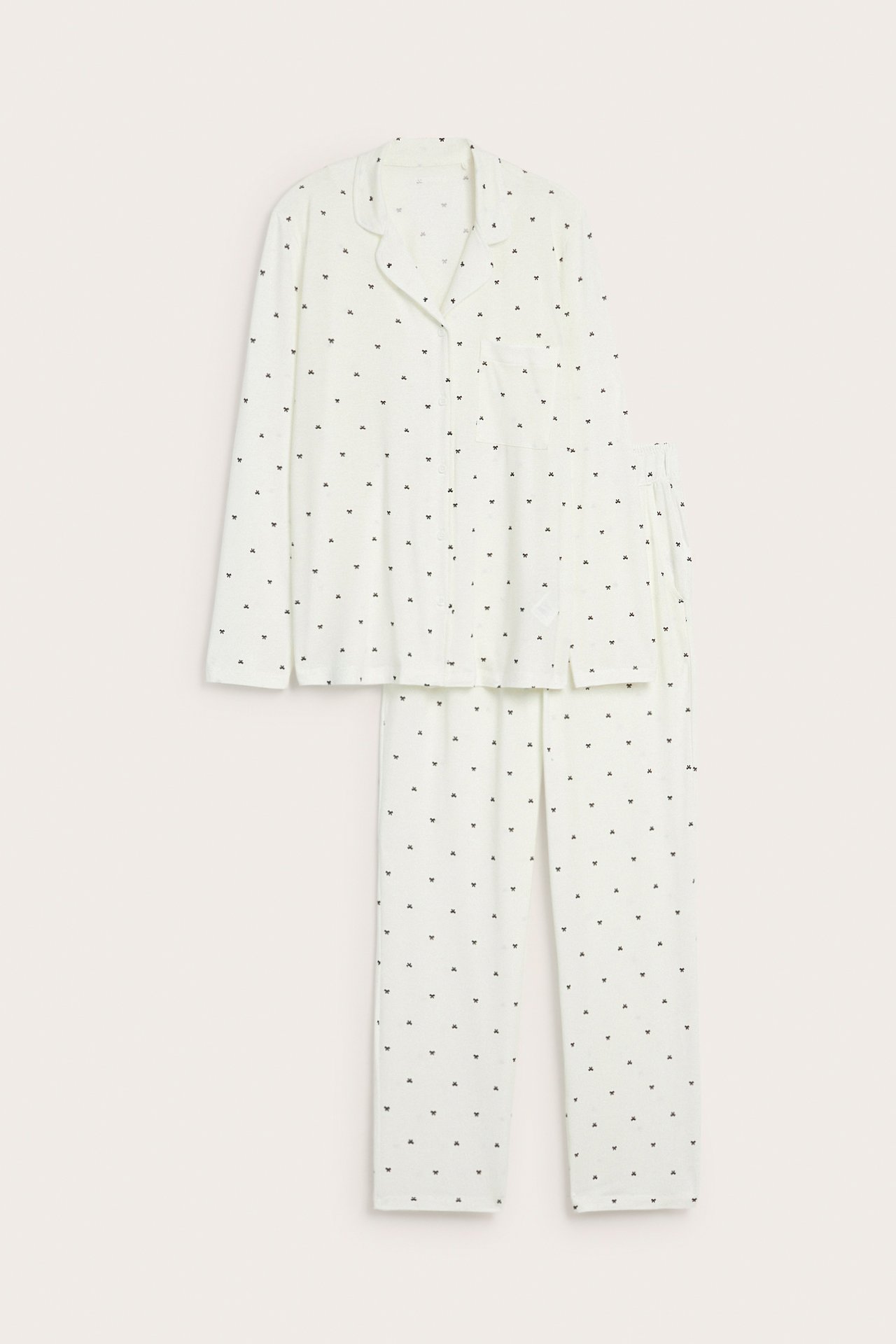Edestä: Luonnonvalkoinen lyocell-pyjama pienellä tummalla kuviolla, napillinen paita ja suorat housut.