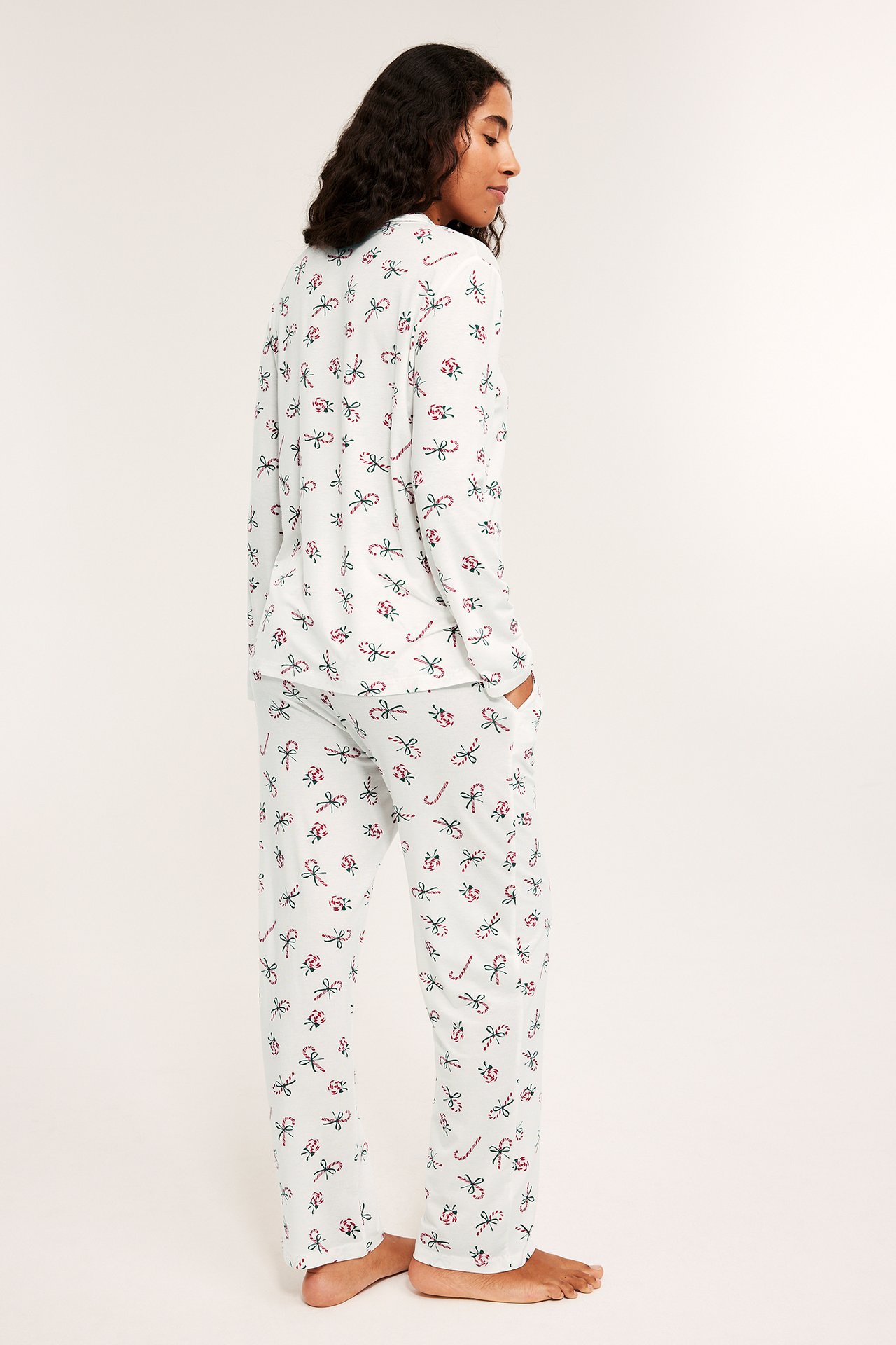 Nainen valkoisessa kuvioidussa pyjamassa, pysähtynyt ja sivutaskut, rento istuvuus.