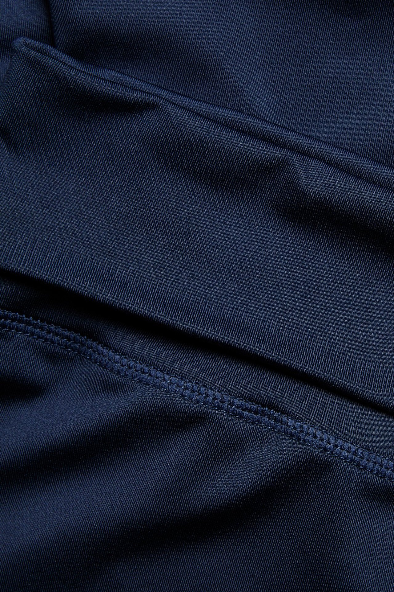 Zbliżenie na granatowy materiał legginsów z poliestru z widocznymi szwami.