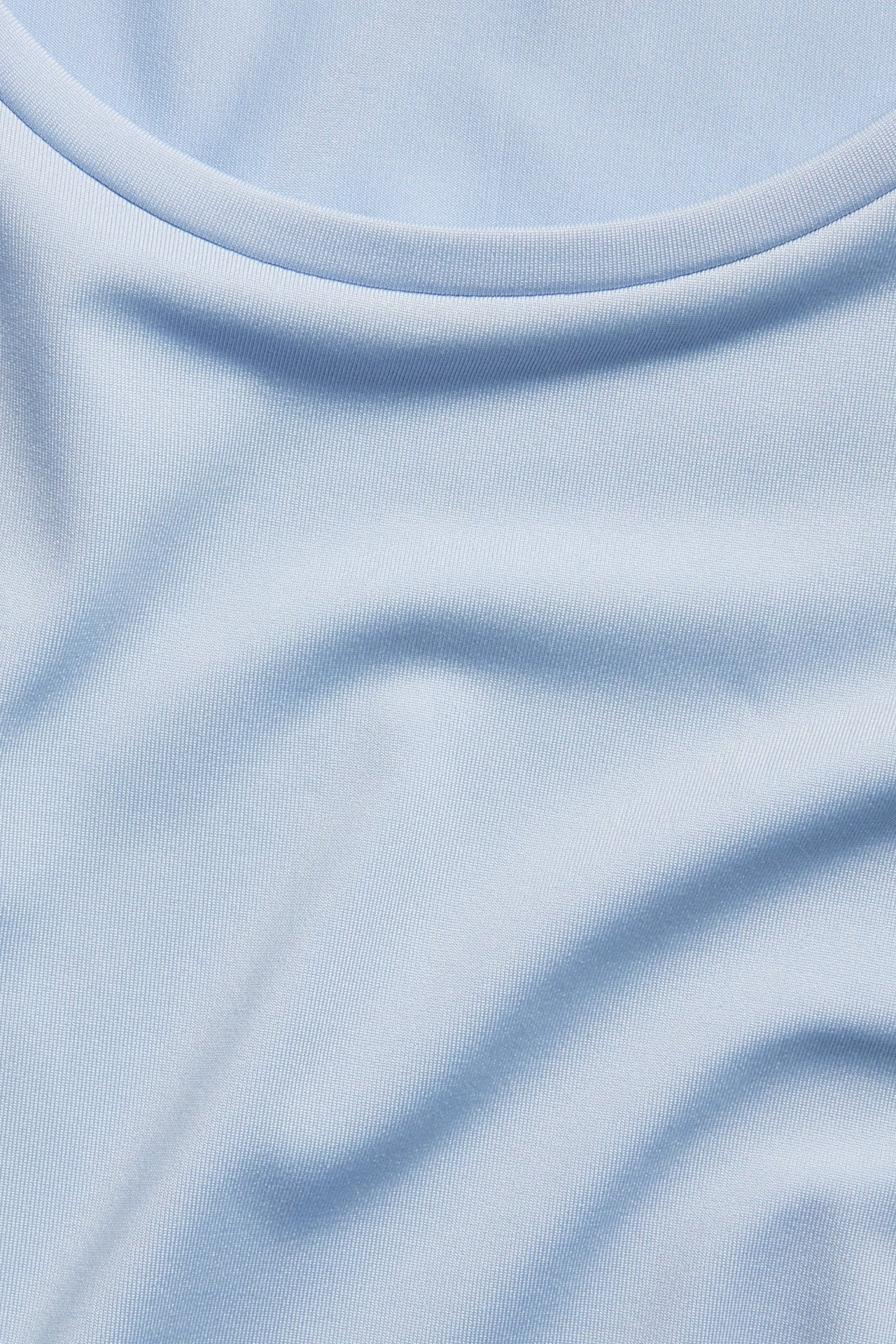 Zbliżenie jasnoniebieskiego, jednolitego, obcisłego topu sportowego z okrągłym dekoltem, z mieszanki poliestru.