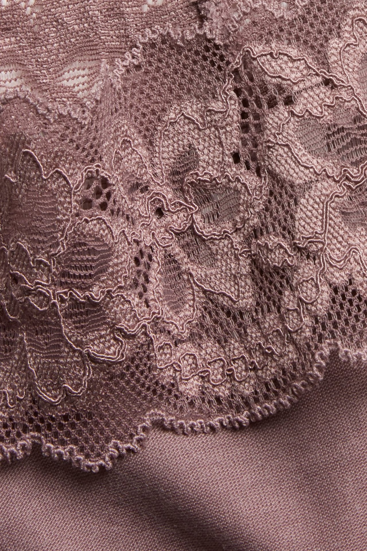 Zbliżenie na ciemnoróżowe stringi lyocell z koronkowym wykończeniem.