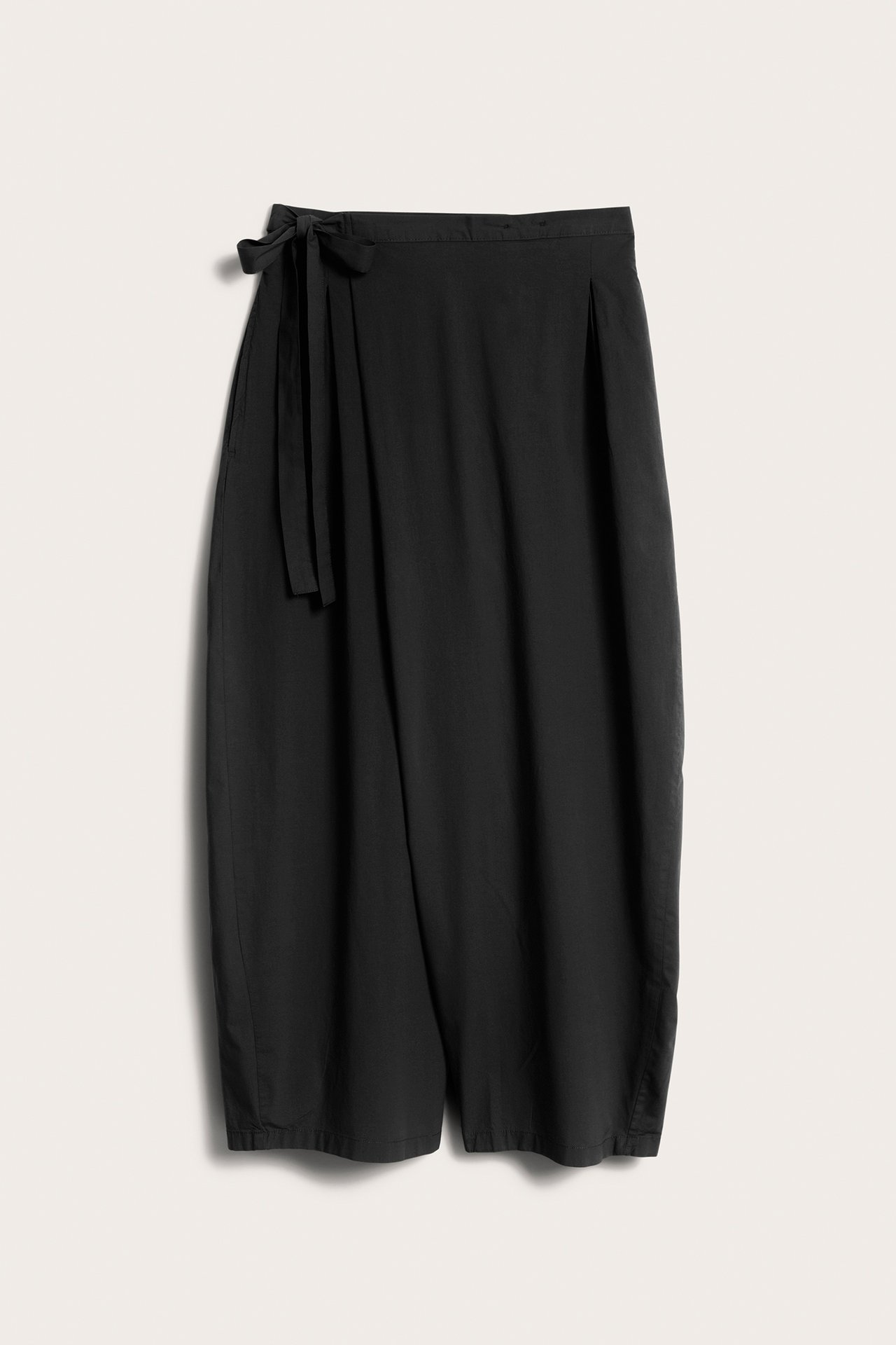 Widok z przodu na czarne, szerokie spodnie kopertowe z popeliny z guzikiem i wiązaniem.