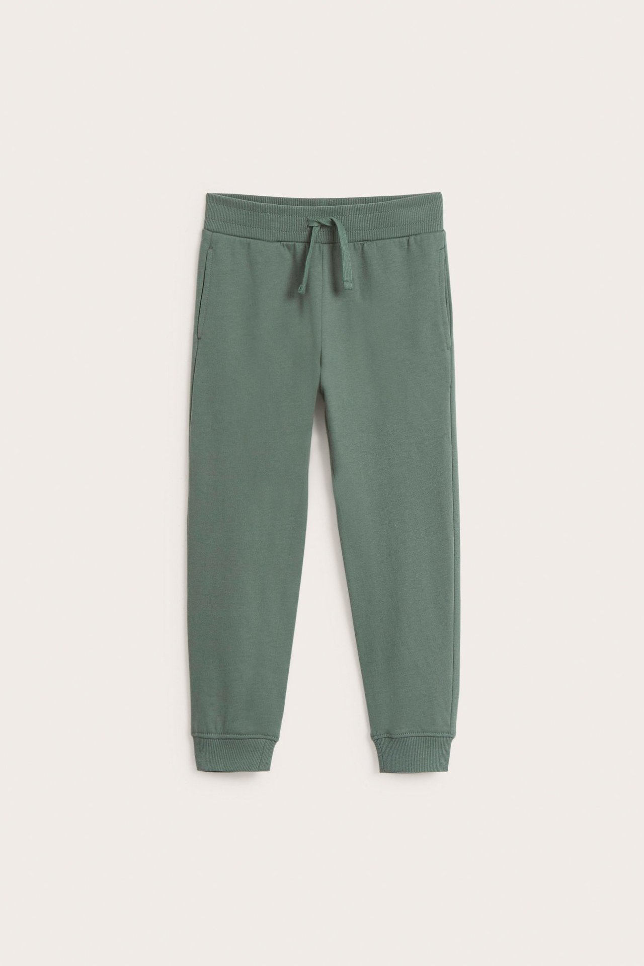 Widok z przodu: ciemnozielone bawełniane spodnie dresowe ze ściągaczem w pasie, sznurkiem, kieszeniami i mankietami.