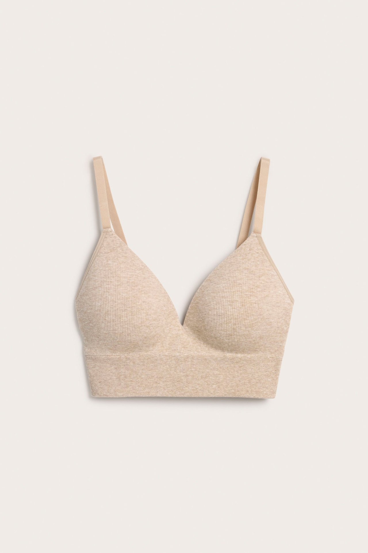 Framifrån: en melerad beige sömlös mjuk bh i ribbad bomullsmix med justerbara axelband.