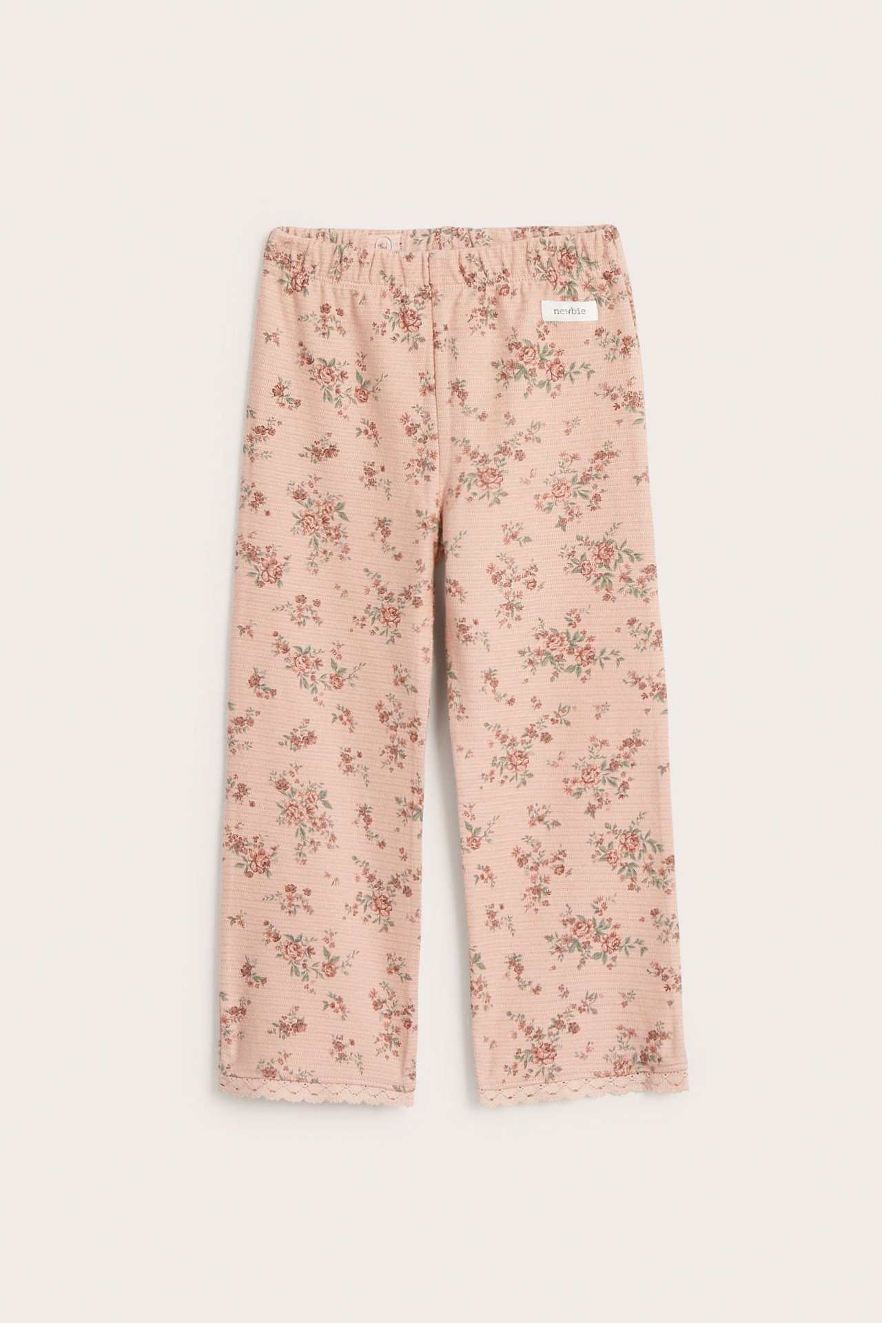 Widok z przodu różowych rozszerzanych legginsów niemowlęcych z dżerseju w kwiatowy wzór z koronką.