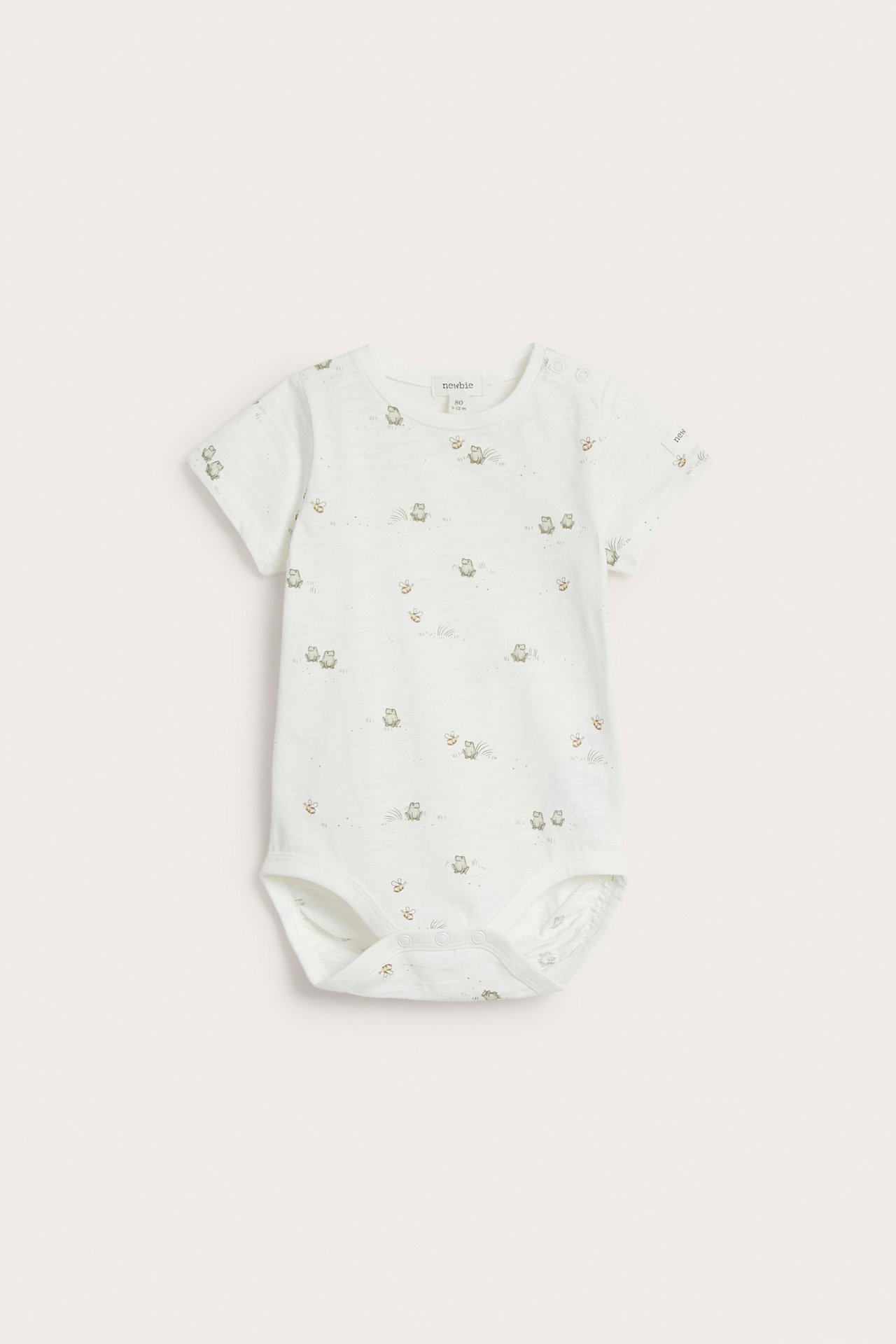 Frontvy av en offwhite kortärmad babybody i bomull med grodmönster och tryckknappar.